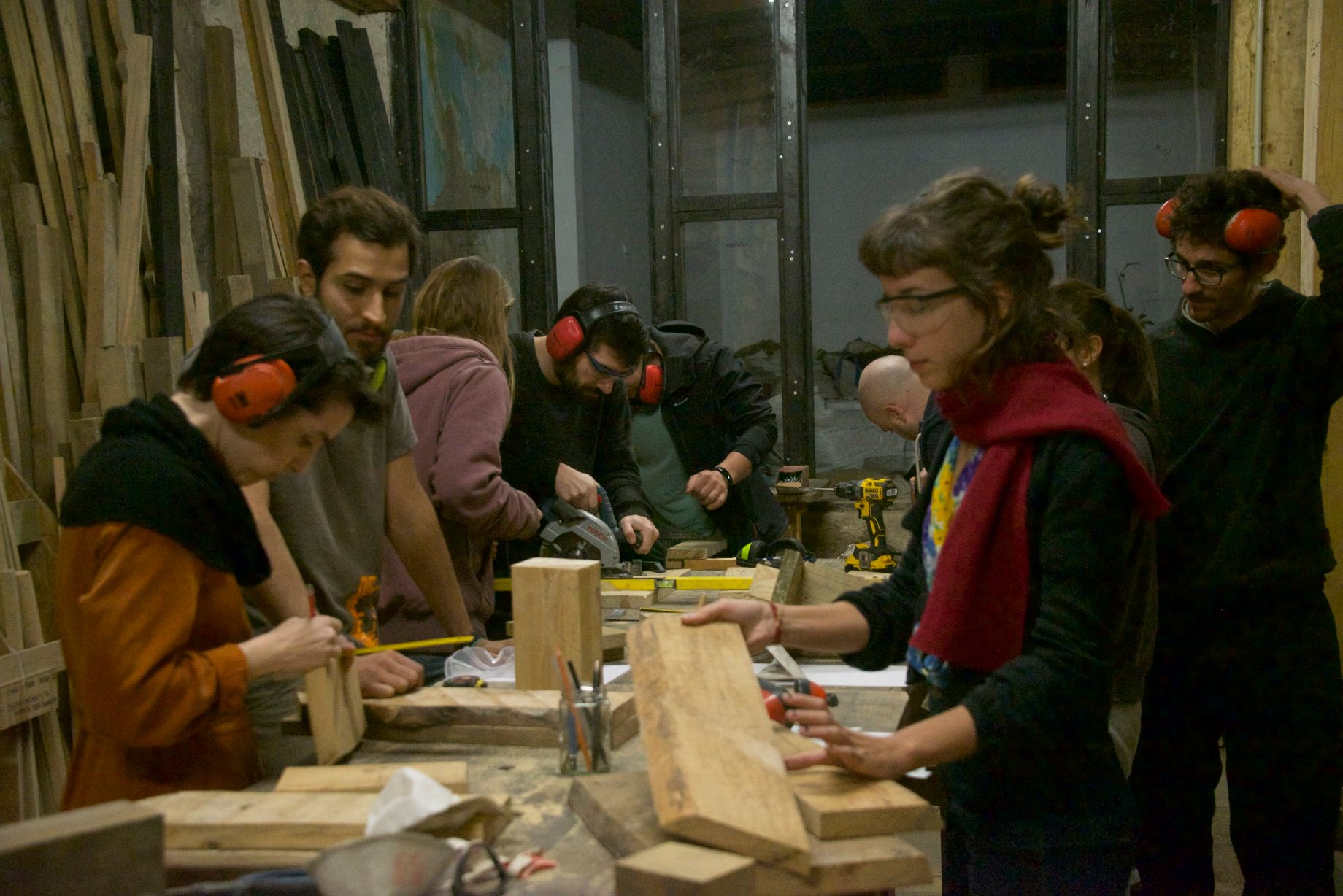 Groupe de participants travaillant le bois autour d'établis en atelier