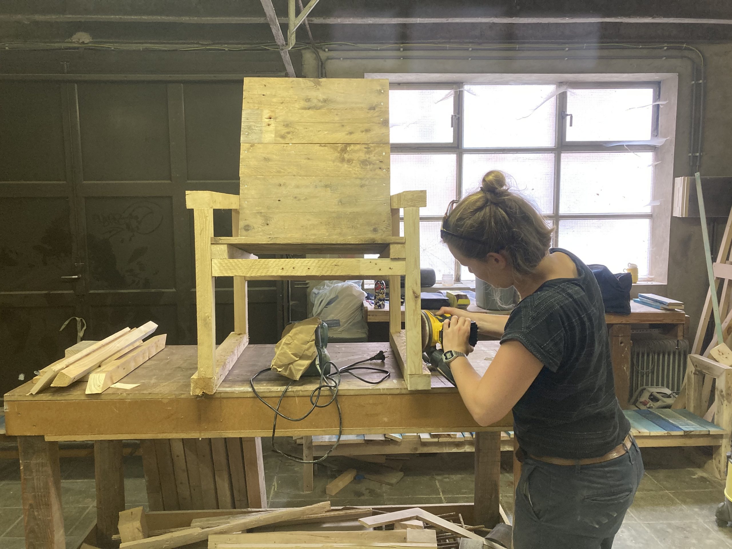 Une participante ponce une chaise en bois dans l'atelier