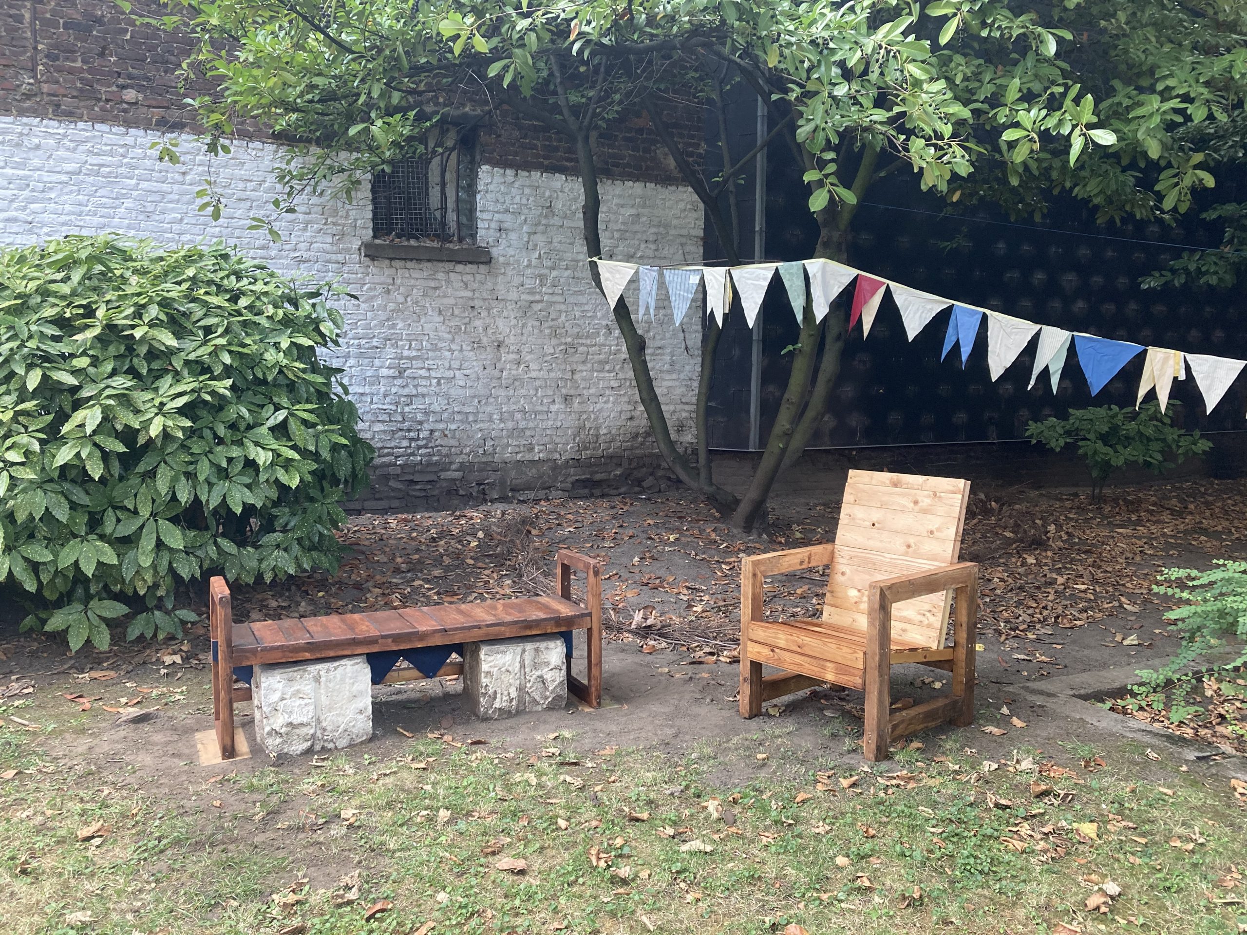 Banc et fauteuil en bois dans le jardin, guirlande de fanions