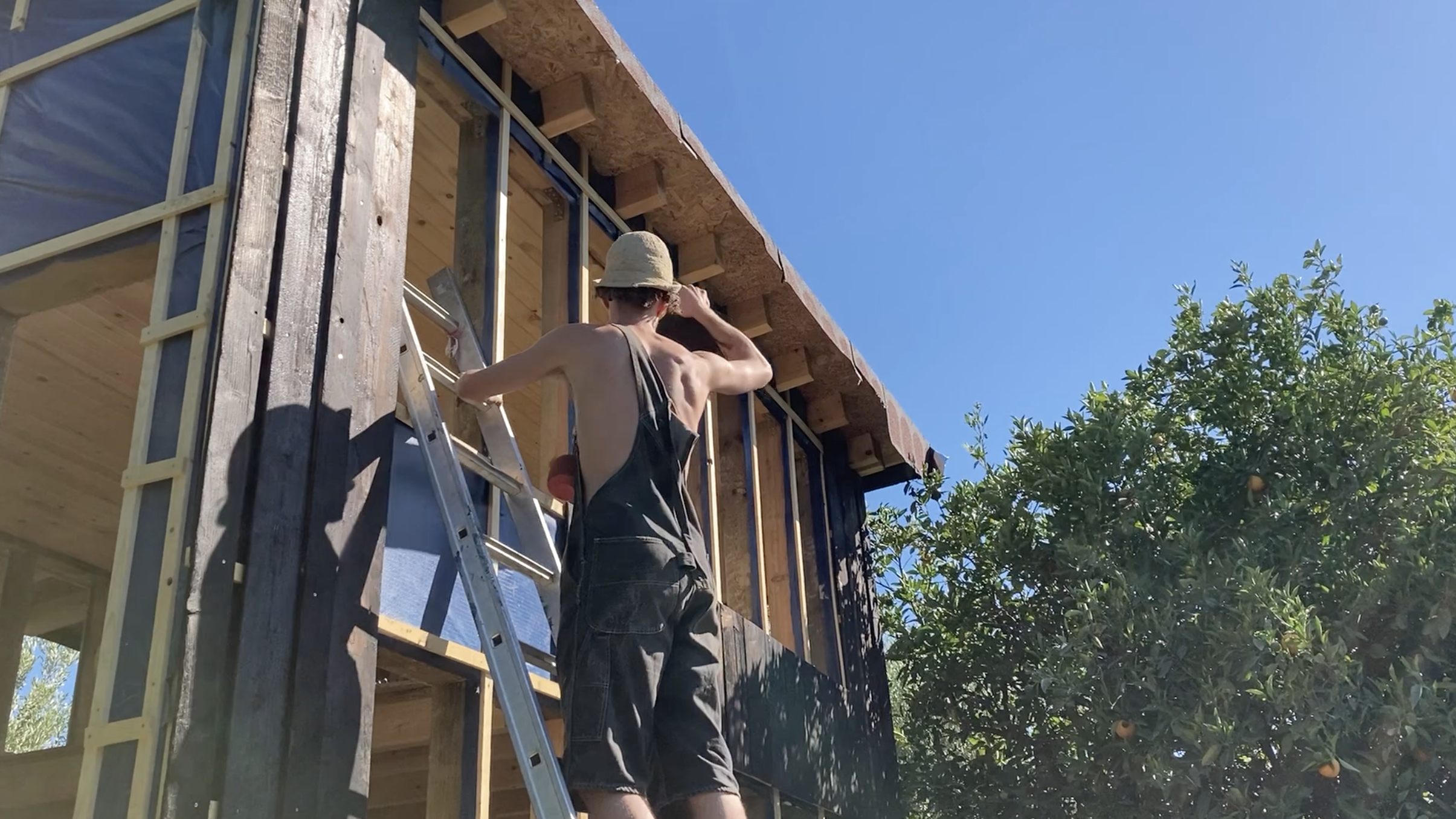 Un participant pose un panneau vitré sur la façade du mini habitat
