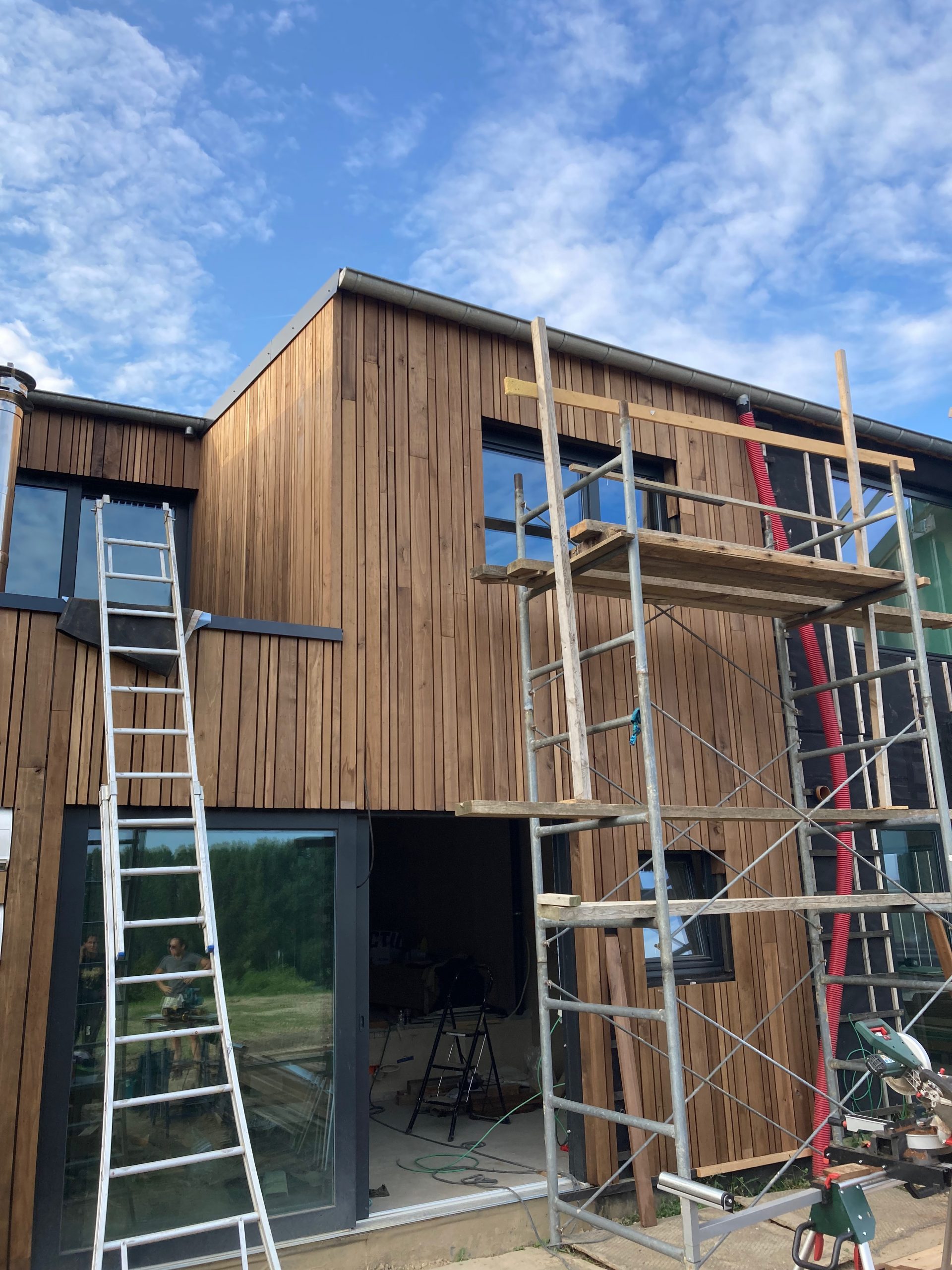 Maison en ossature bardée de bois, échafaudage et échelles en façade