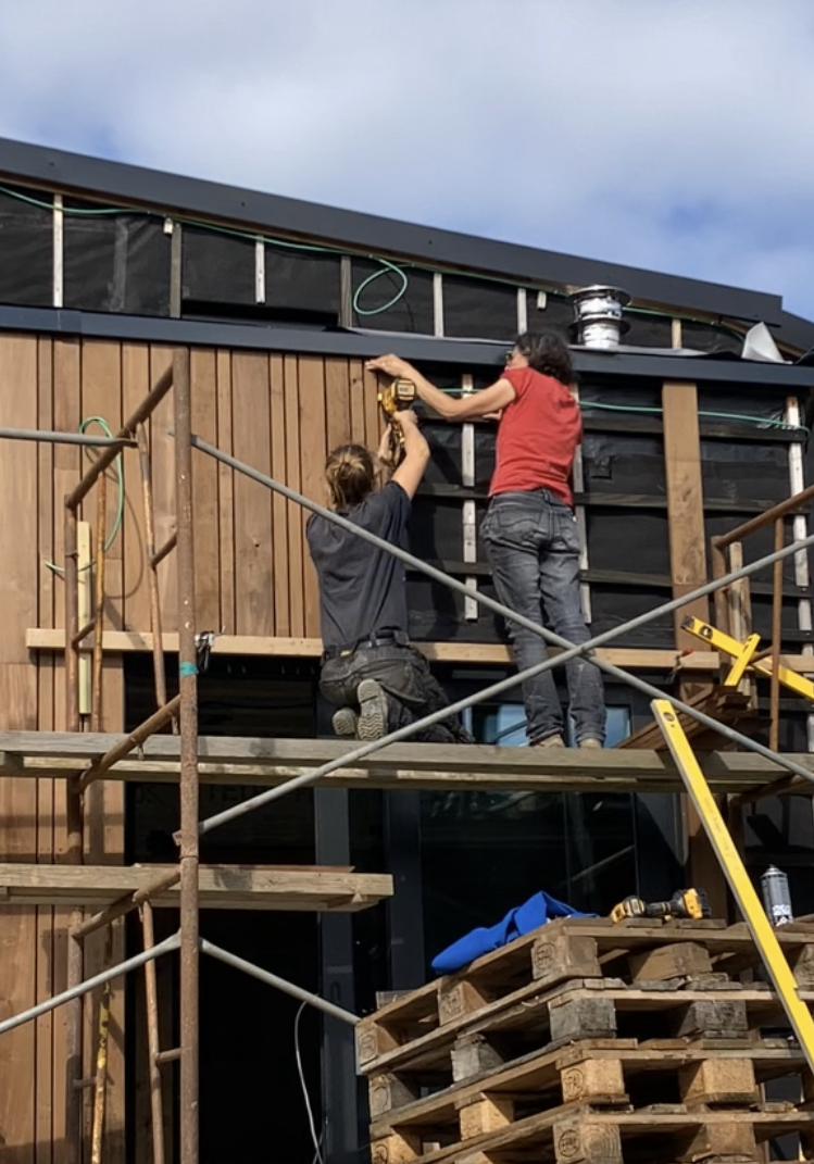 Deux participants posent le bardage sur un échafaudage