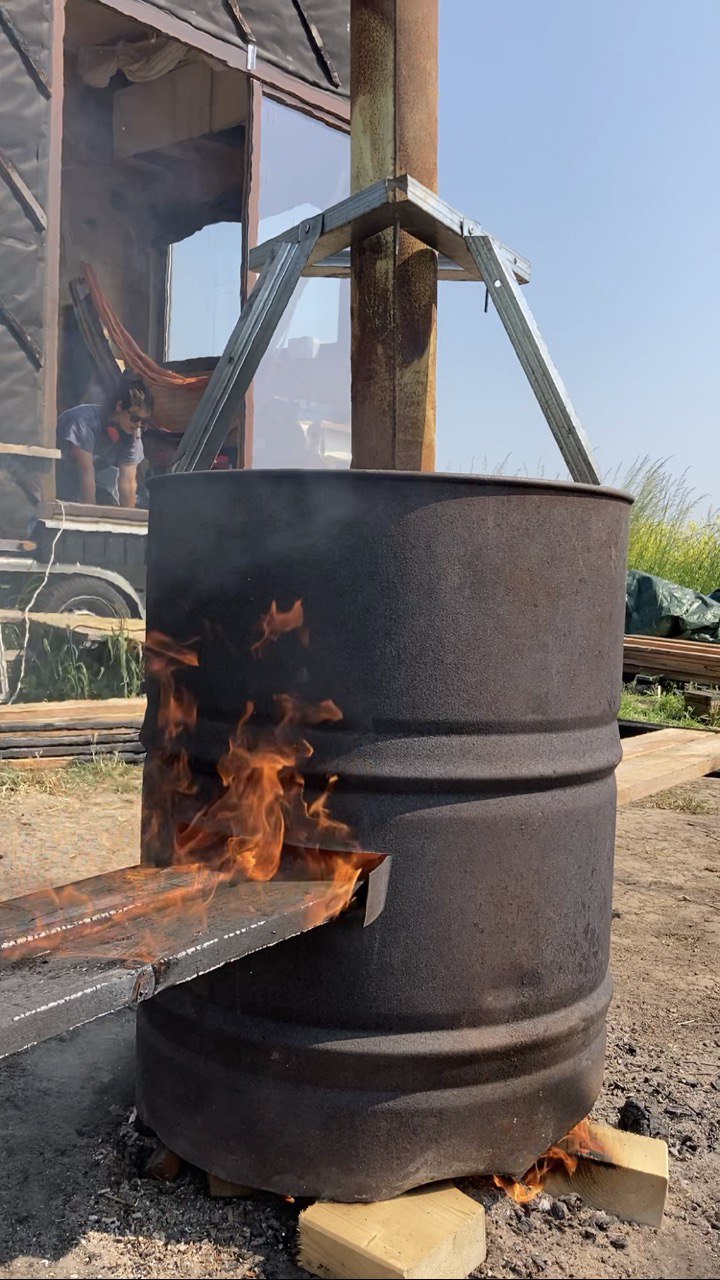 Brûlage des planches dans un fût sous un auvent, flammes vives