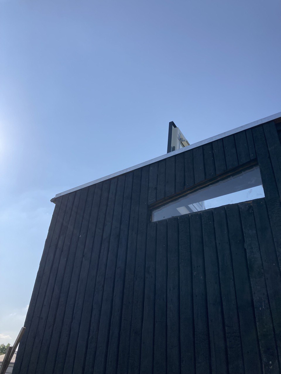 Faîtage et bardage bois brûlé se découpant sur le ciel