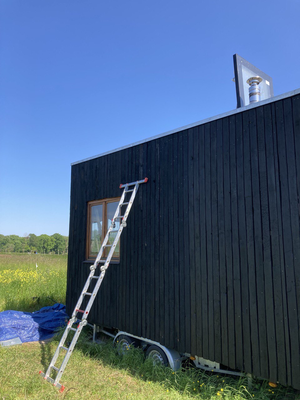 Le bâtiment bardé de bois brûlé dans un champ, échelle en façade