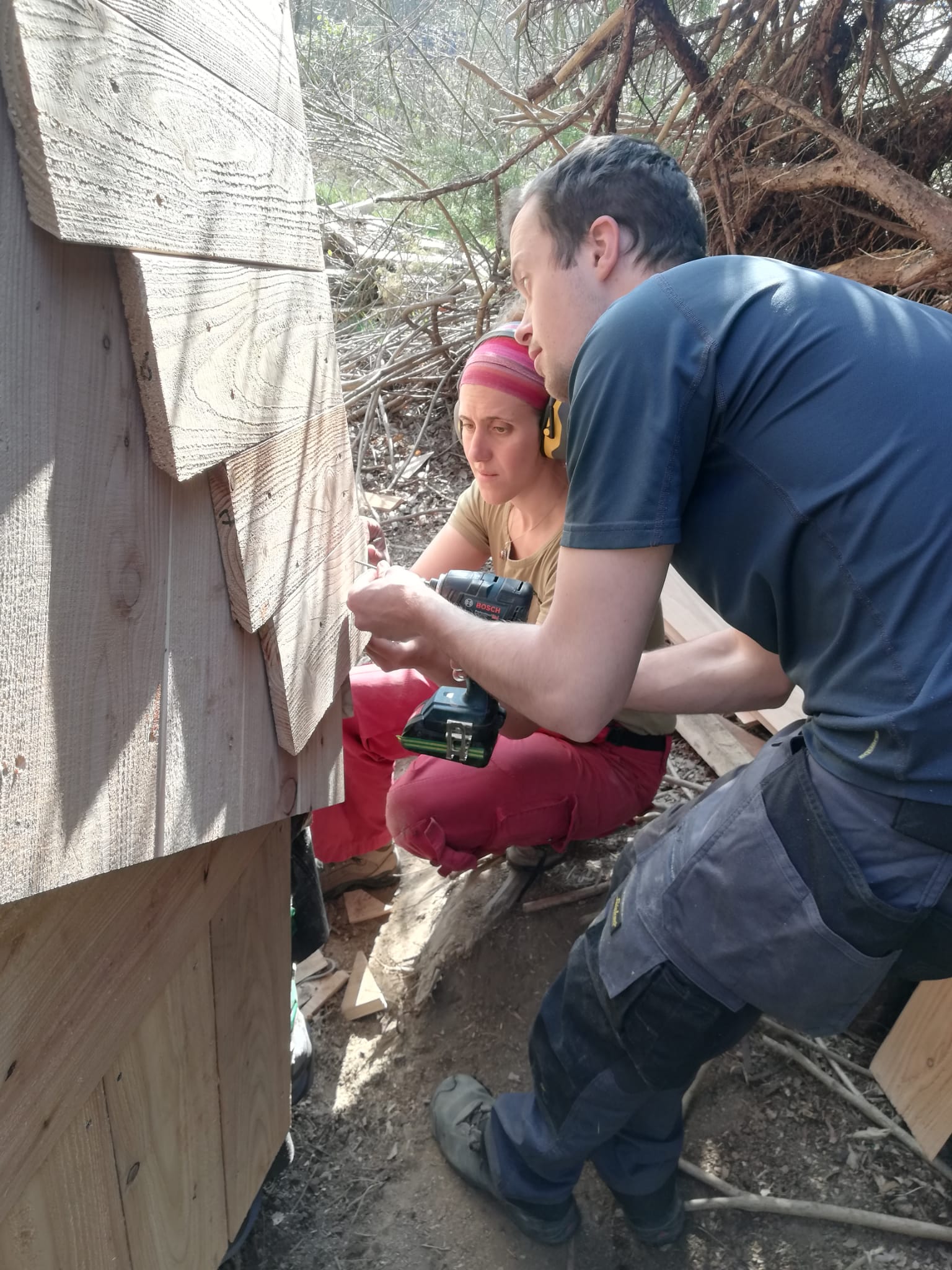 Participants ajustant le bardage à la base du dôme