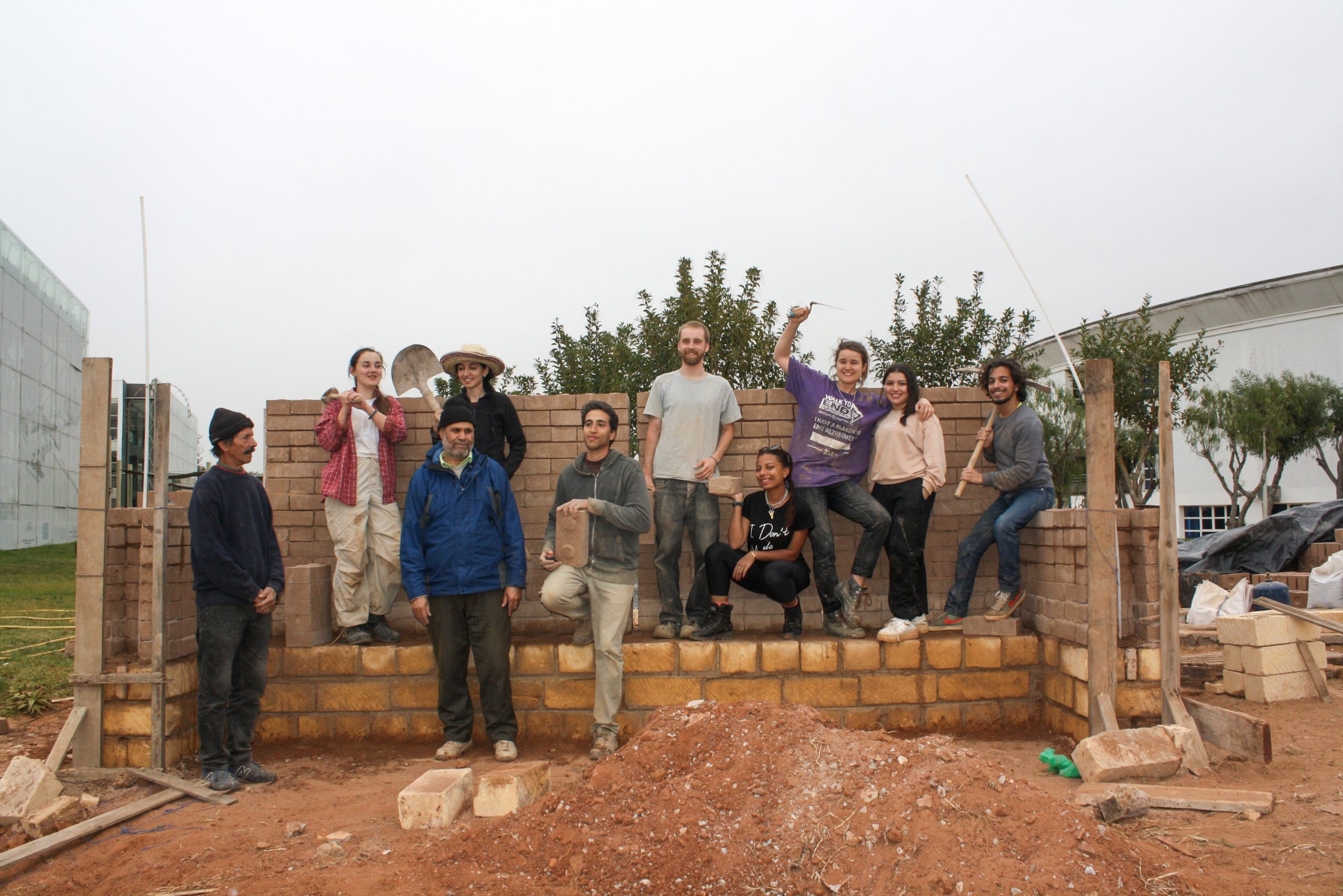 Le groupe posant derrière le mur de briques de terre en construction