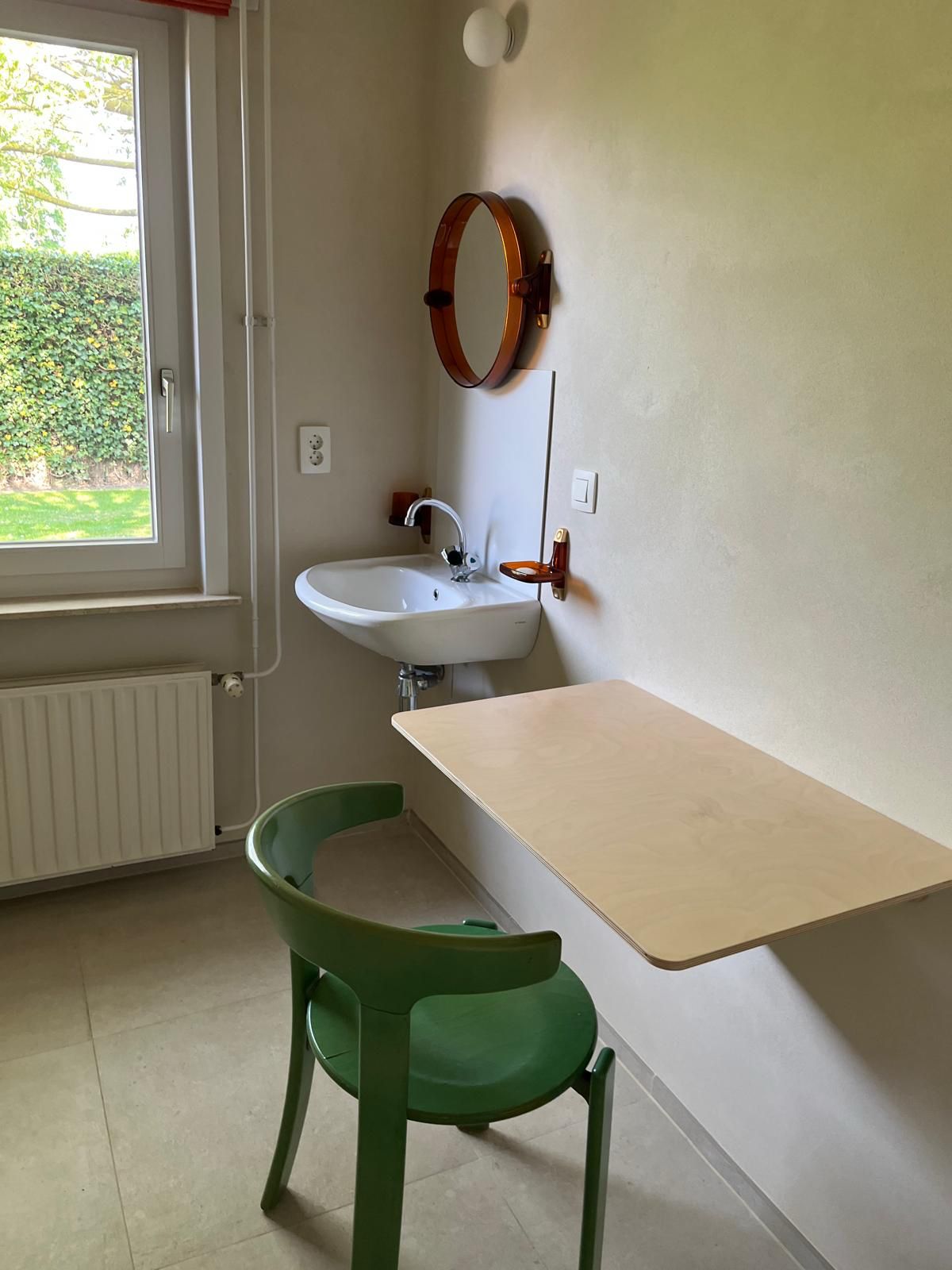 Petite salle d'eau rénovée, lavabo mural et tablette sur un mur enduit à la chaux, chaise verte