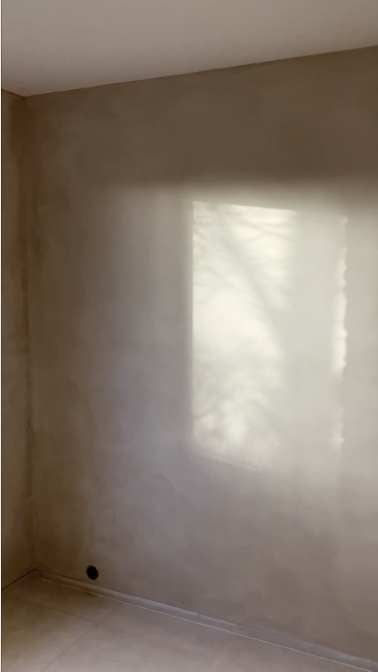 Pan de mur enduit à la chaux éclairé par une lumière rasante