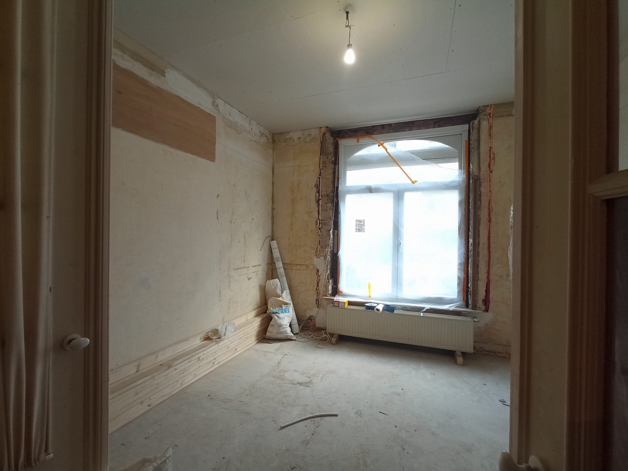 Chambre en cours de rénovation, murs enduits à la chaux et sol de chantier