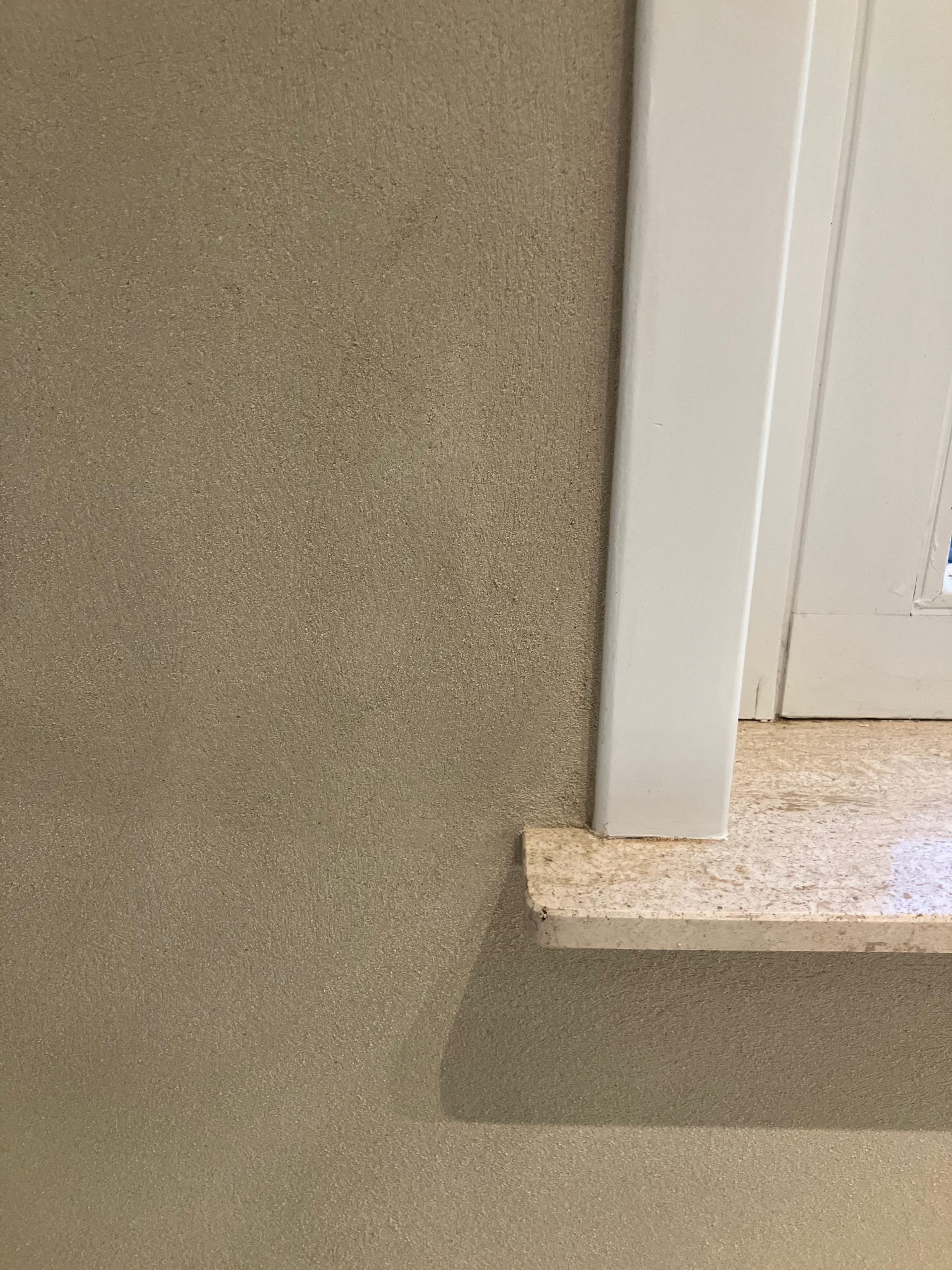 Embrasure de fenêtre enduite à la chaux avec appui en bois brut