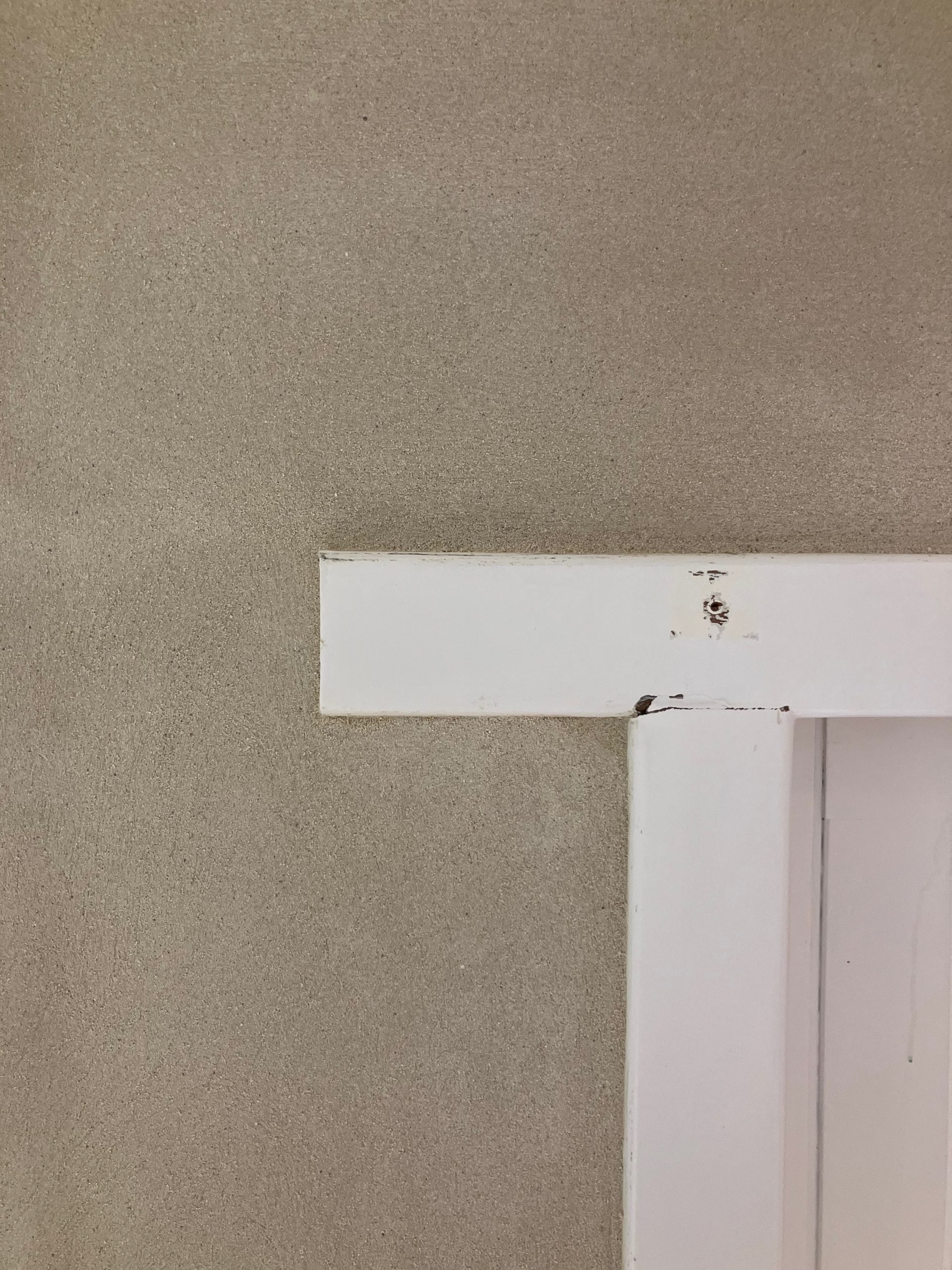 Détail d'un linteau blanc au-dessus d'un mur enduit à la chaux