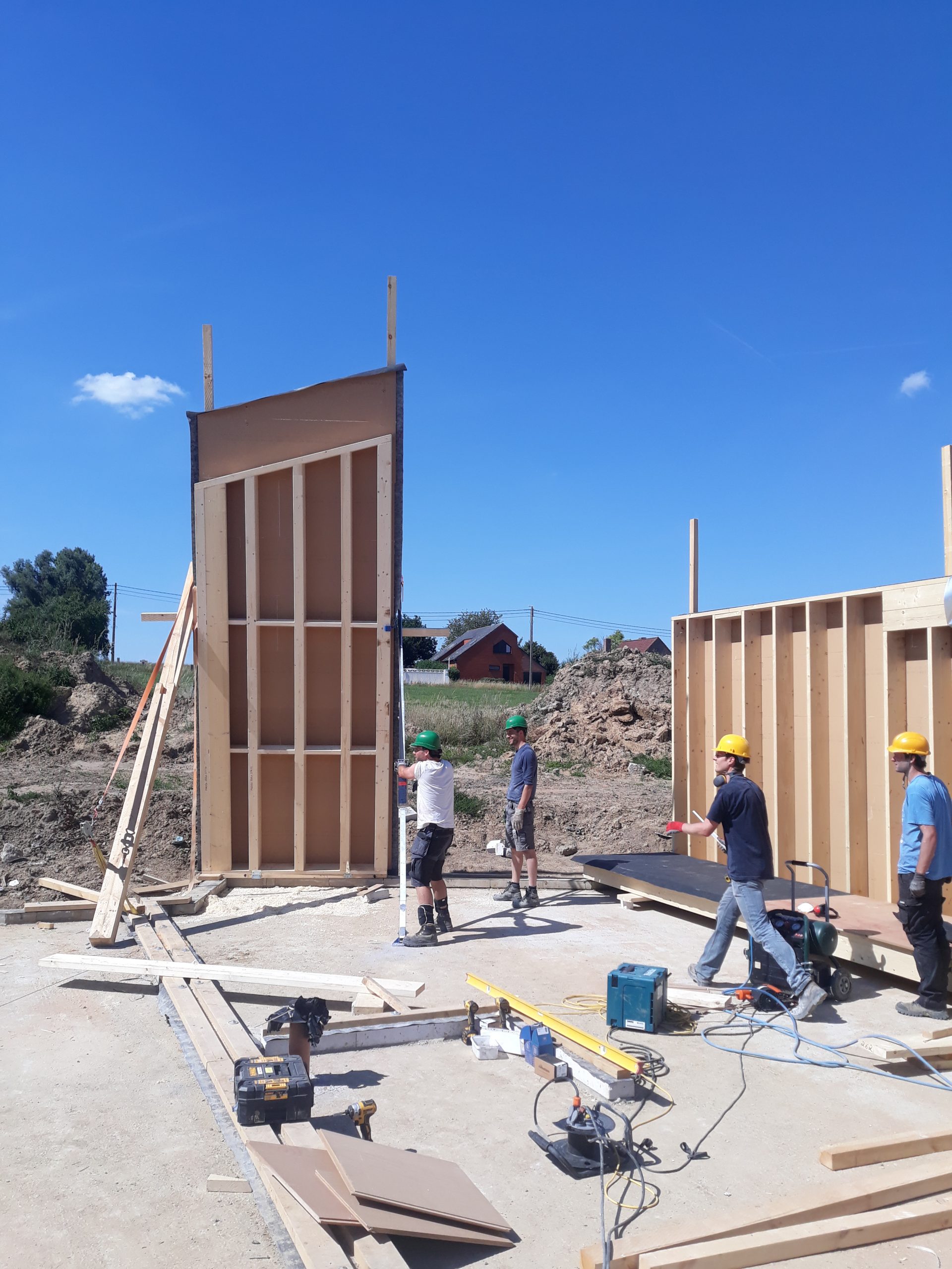 Panneaux de mur en ossature bois dressés sur le chantier-école, ciel bleu
