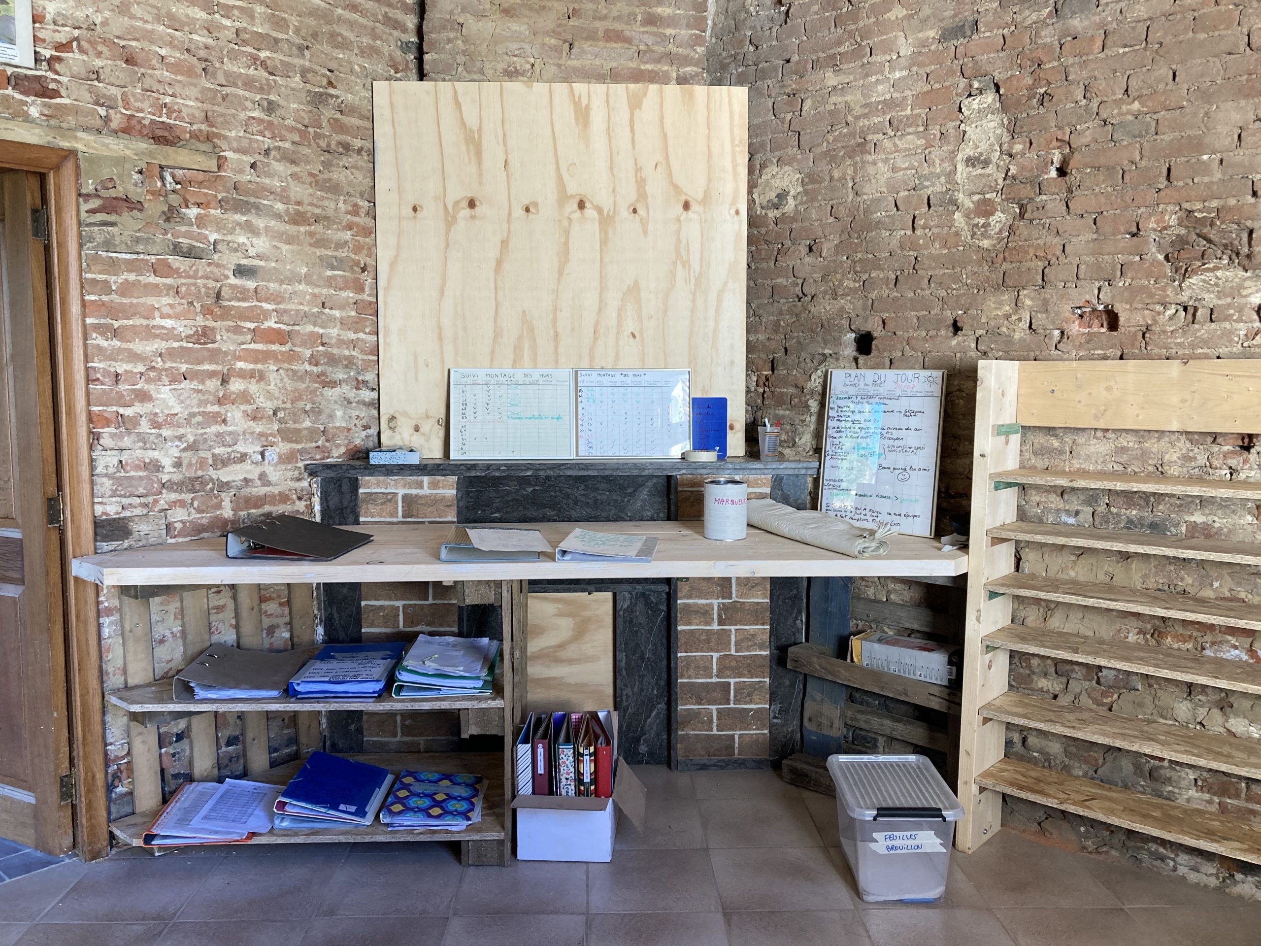 Atelier de préparation avec établis et panneaux, dans une halle en briques