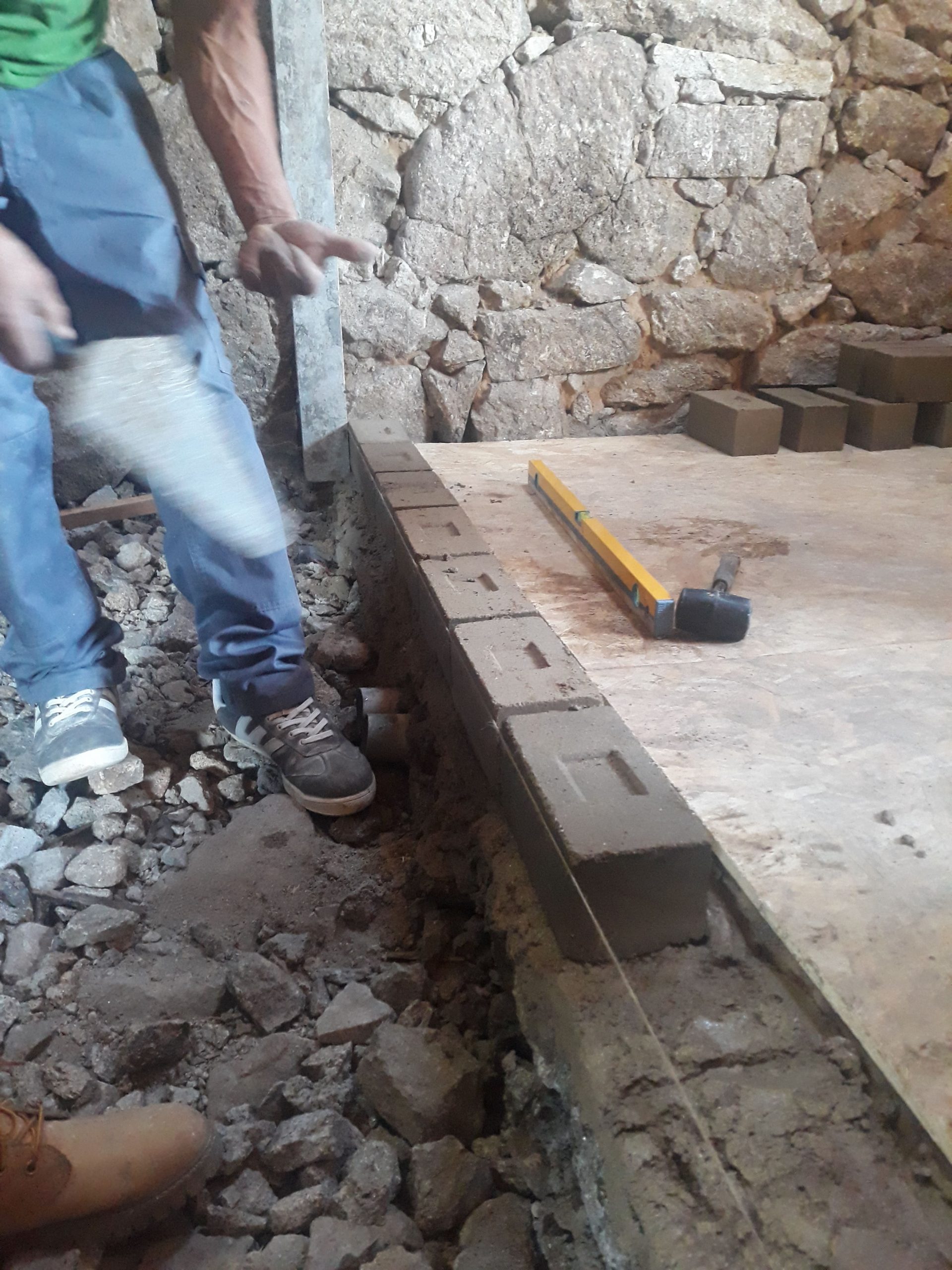 Un participant prépare une fondation près d'un mur en pierre