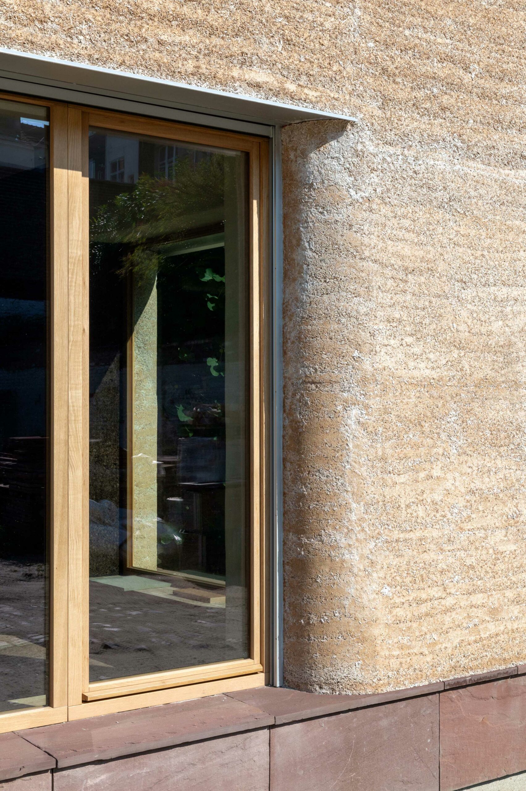 Fenêtre bois posée à fleur d'une façade en chaux-chanvre à coins arrondis