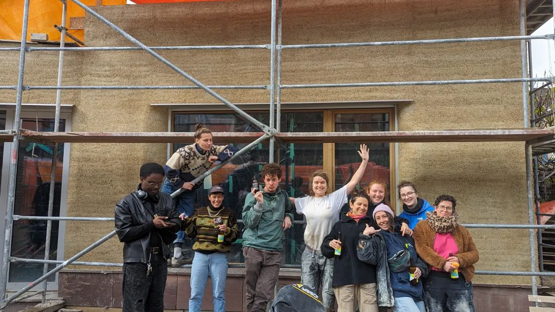Groupe de participants qui pose joyeusement devant la façade