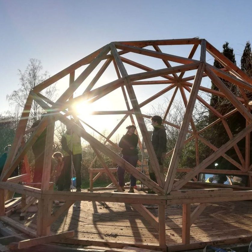 La structure du dôme en bois se découpe sur le soleil couchant
