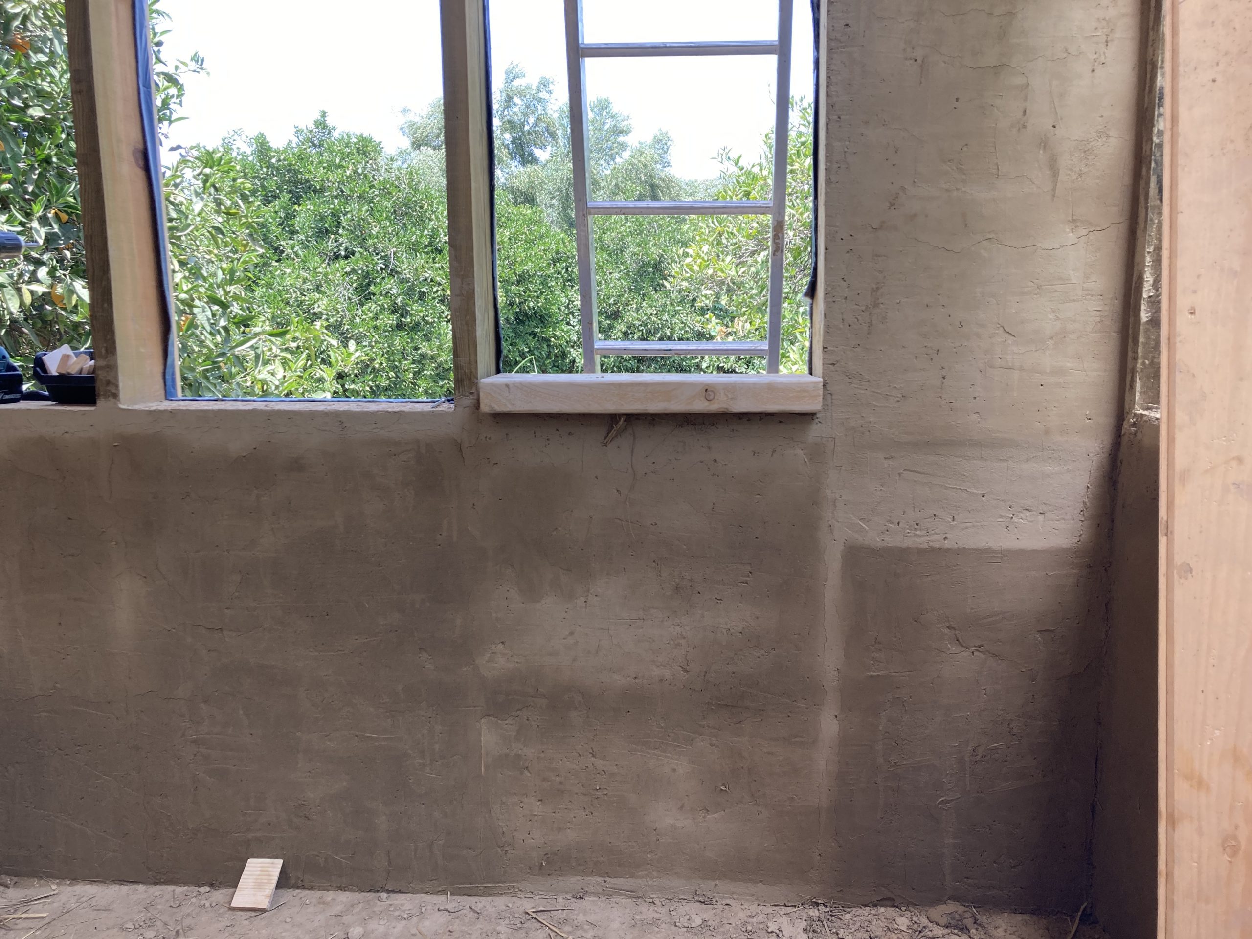 Intérieur du mini habitat, mur enduit sous une fenêtre en bois