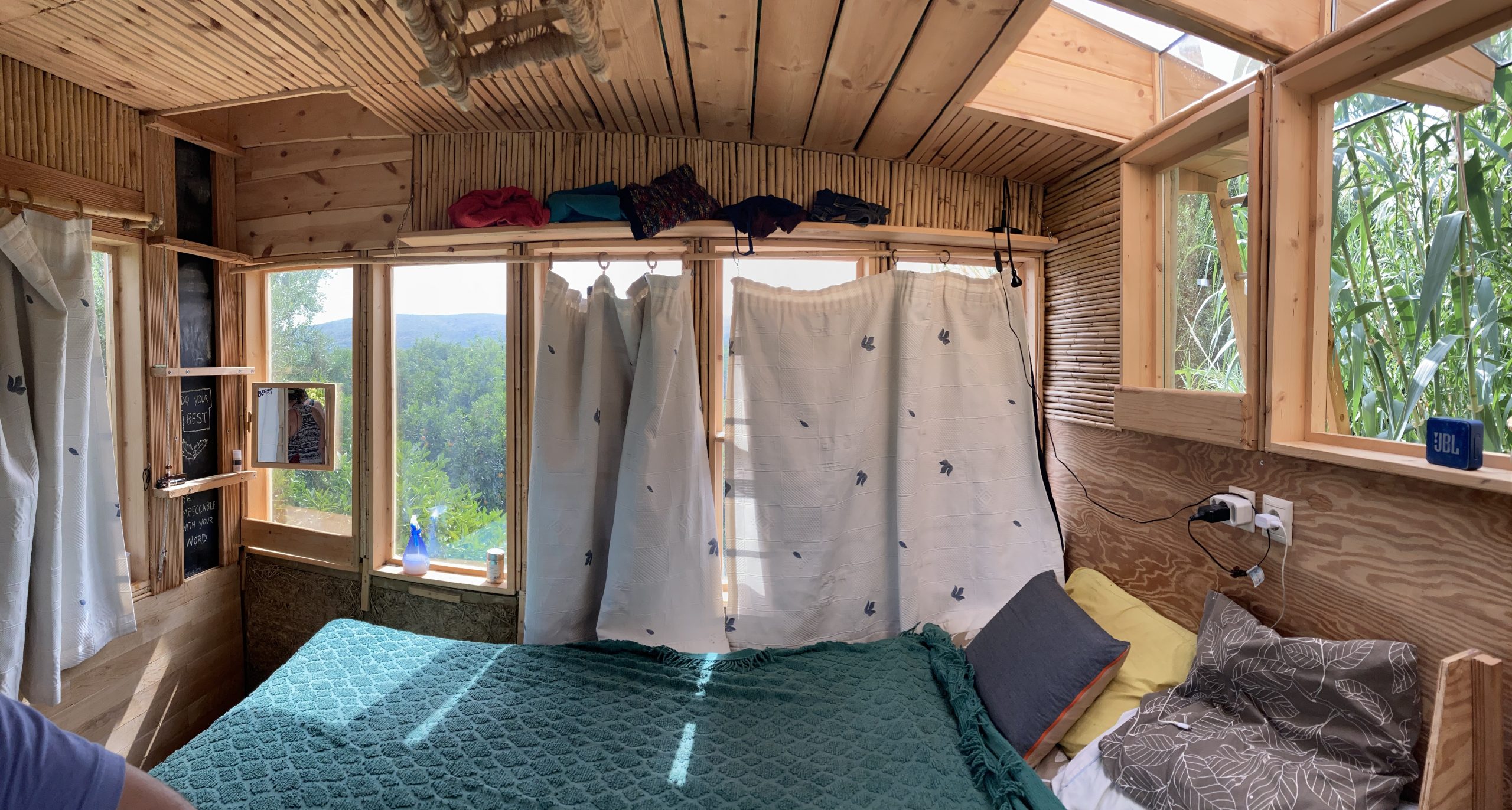 Intérieur en bois du mini habitat, lit face à une baie vitrée