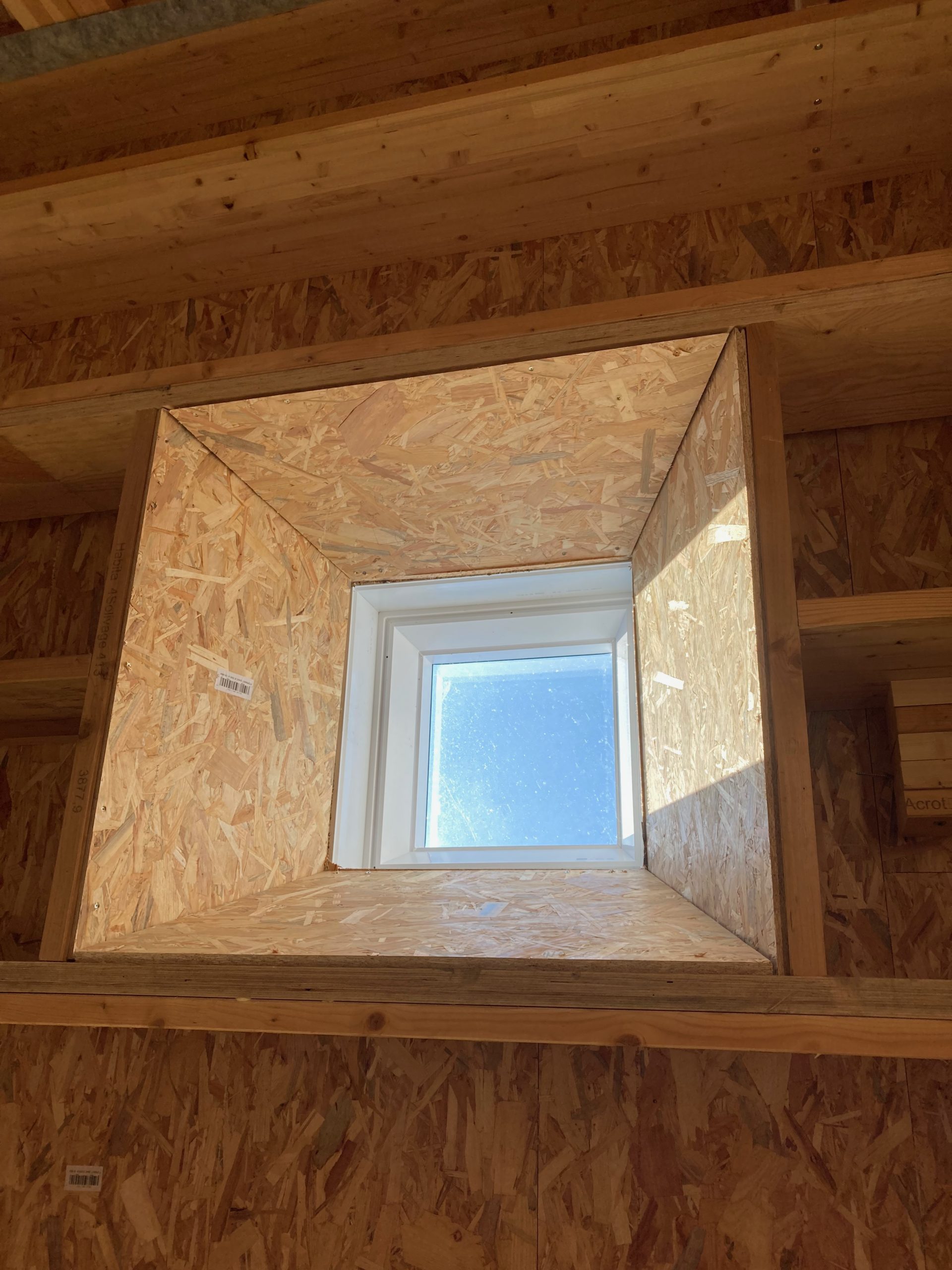Contre-plongée sur une fenêtre de toit dans le plafond en OSB