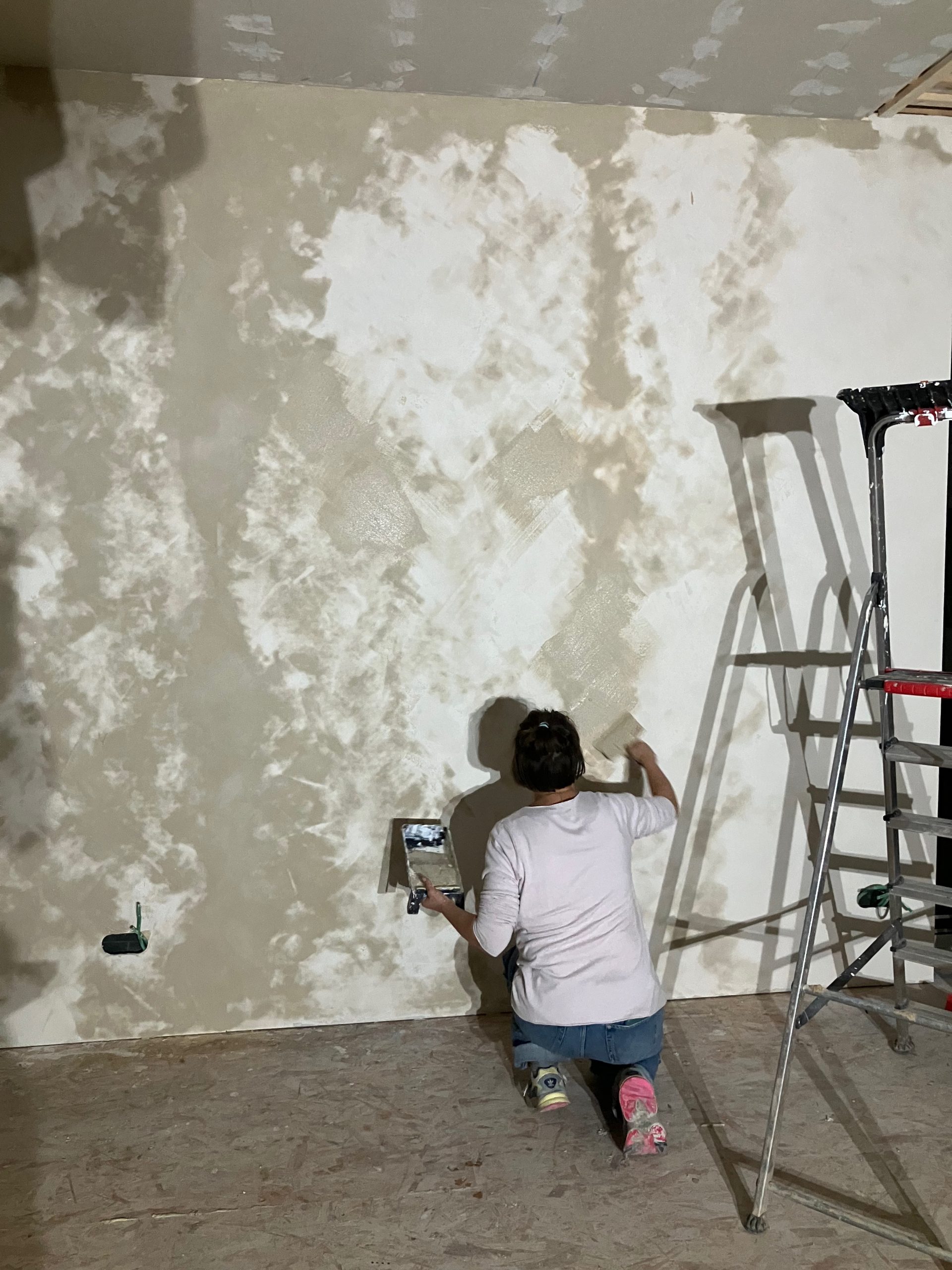 Une participante peint un mur à l'argile, sur un échafaudage