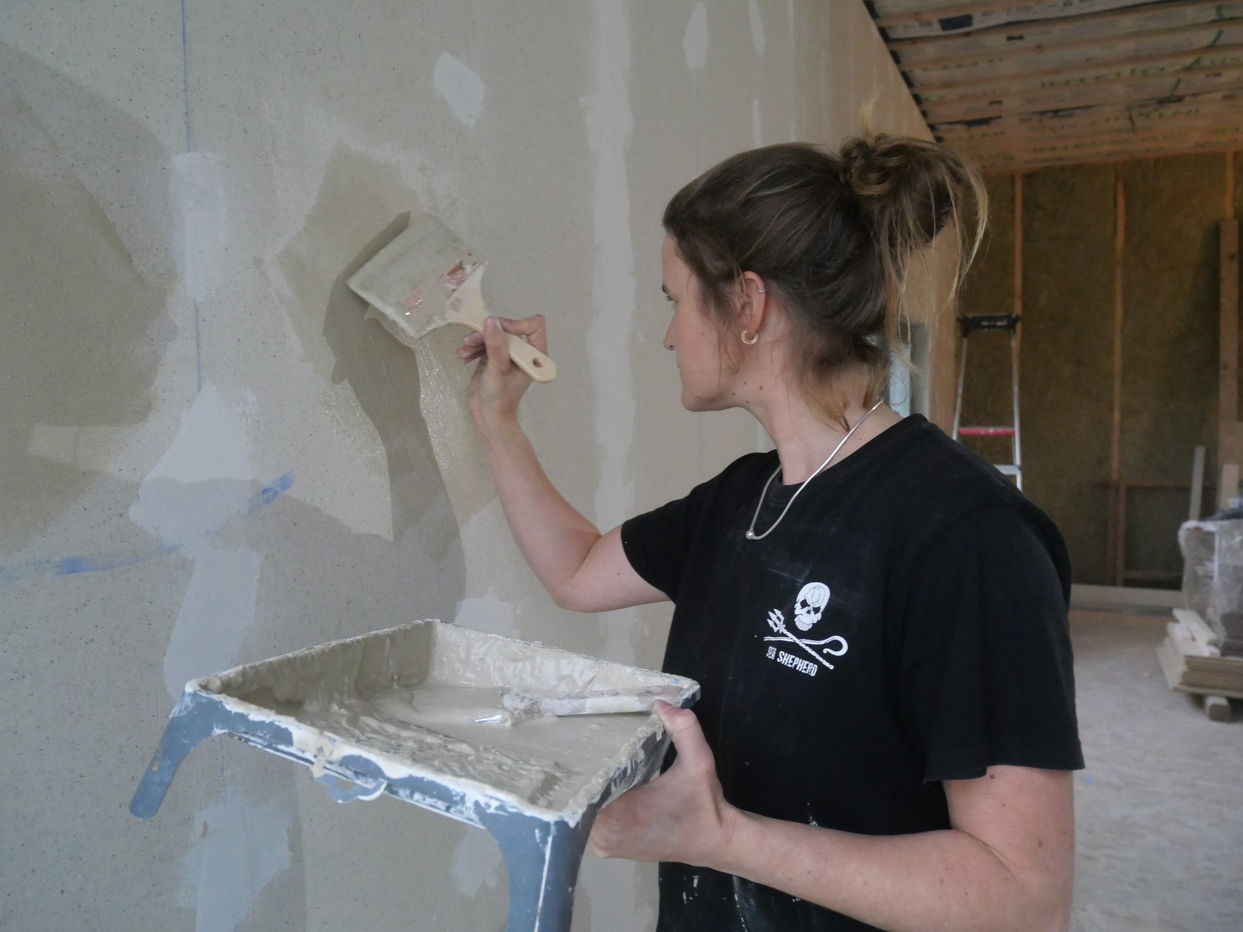Une participante applique la peinture argile au platoir sur un mur