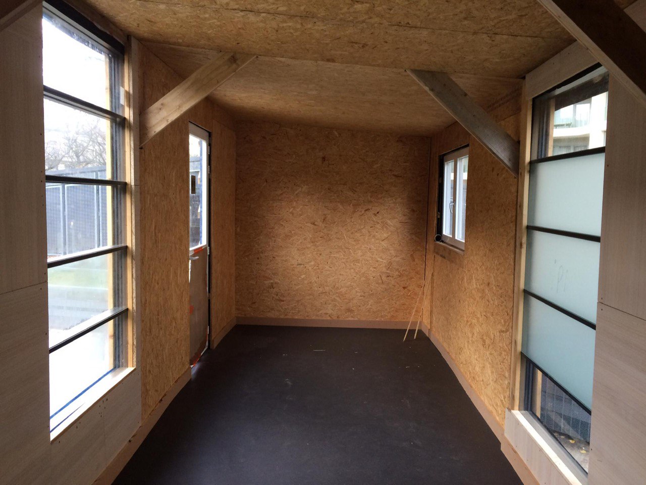 Intérieur du pavillon habillé d'OSB, fenêtres en bandeau et sol foncé