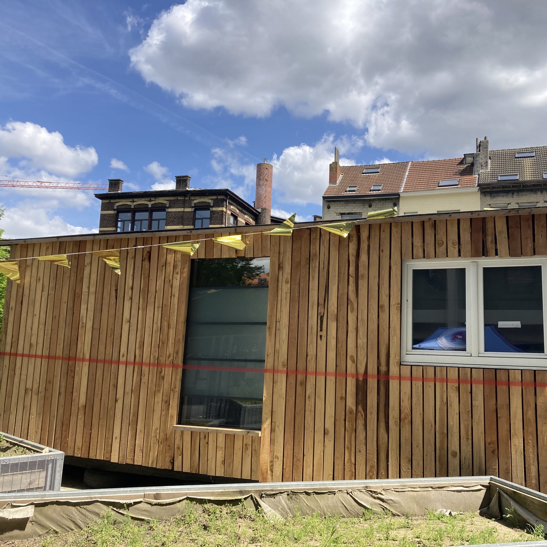 Façade en bardage bois vertical avec grande fenêtre, sous un ciel bleu