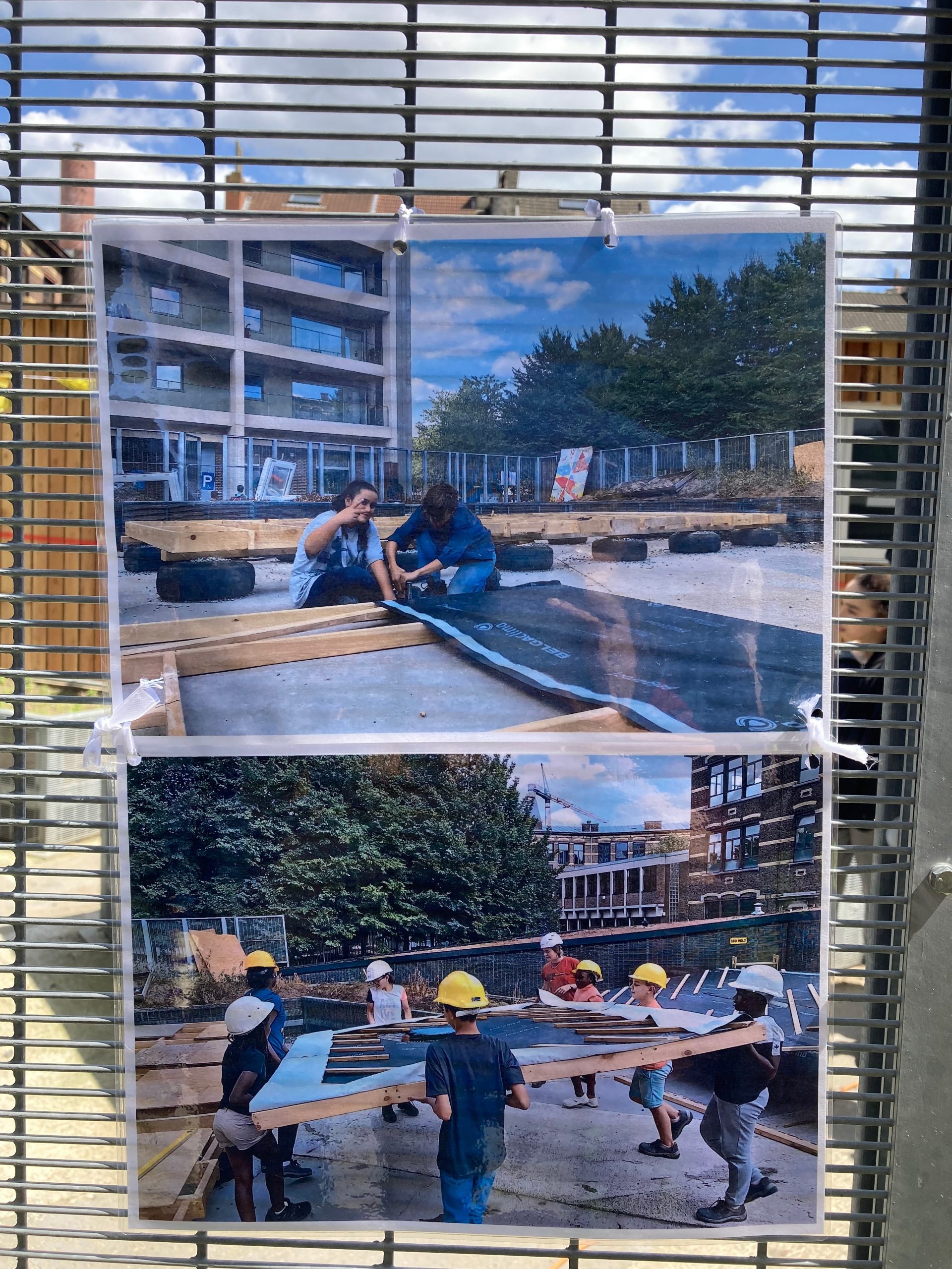 Fenêtre à stores donnant sur un montage photo du chantier participatif