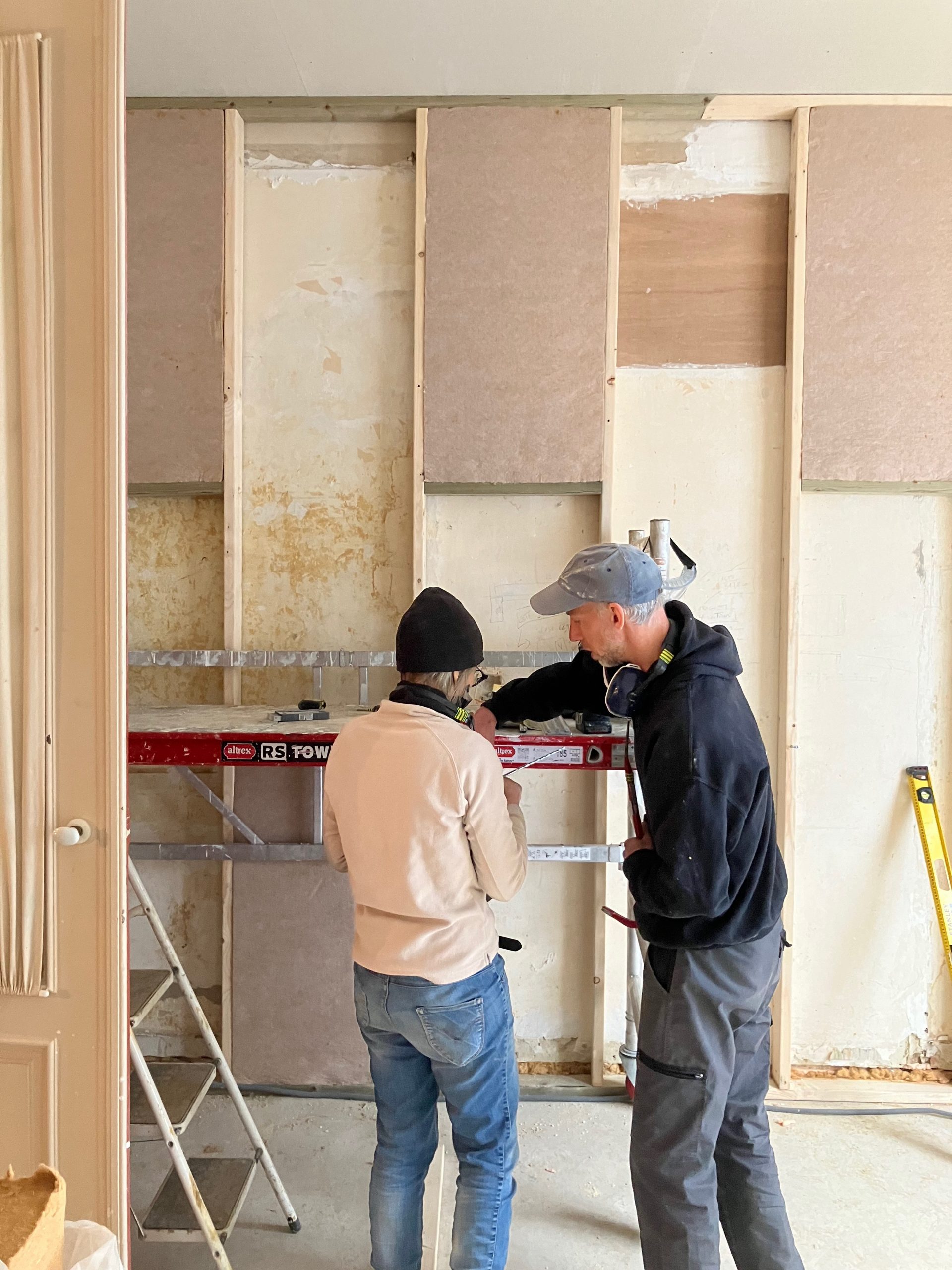 Deux participants discutent devant une cloison en cours de montage