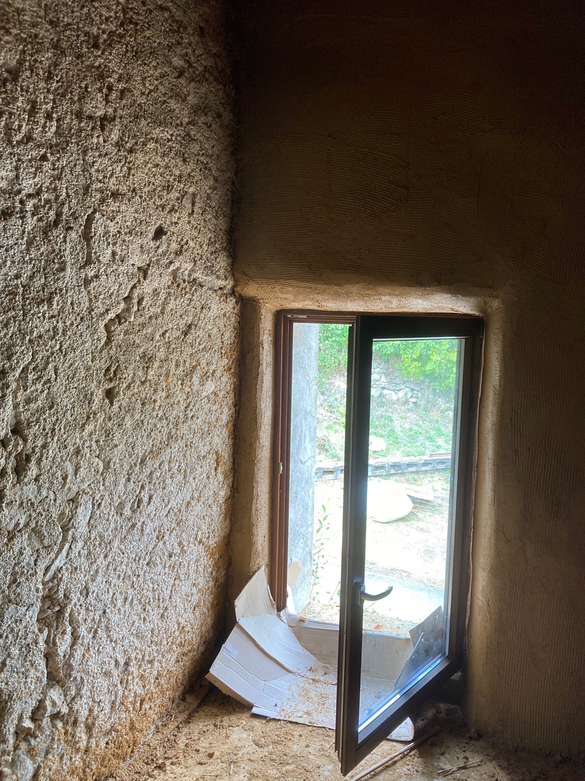 Embrasure de fenêtre enduite en terre dans un mur en paille