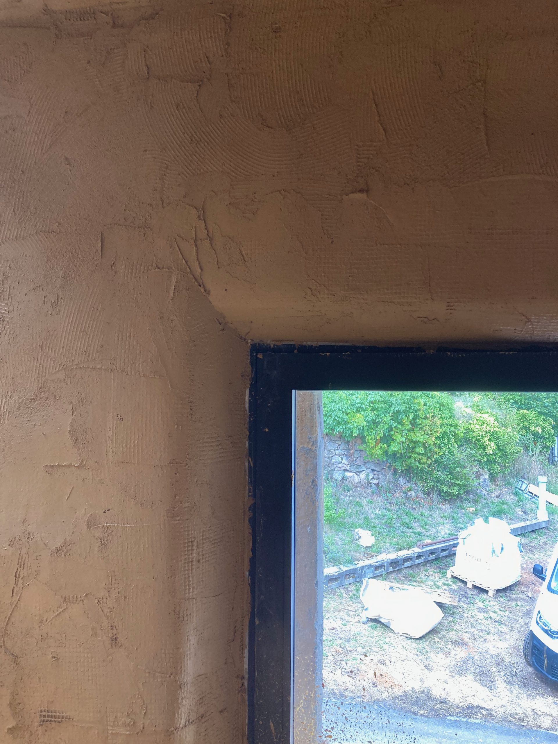 Fenêtre ouverte sur la campagne dans un mur épais enduit en terre