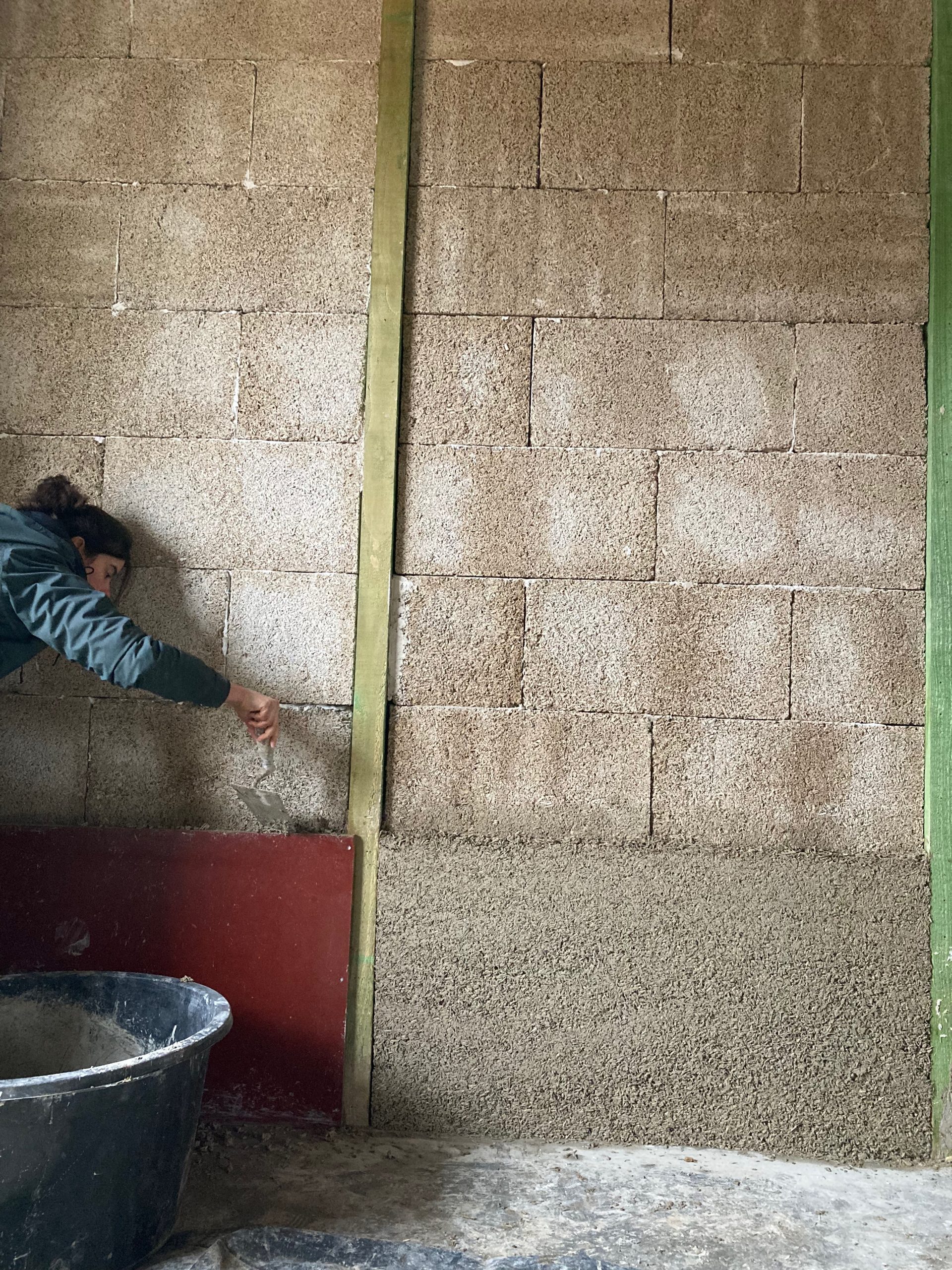 Un participant tasse le béton de chanvre le long d'un mur en blocs
