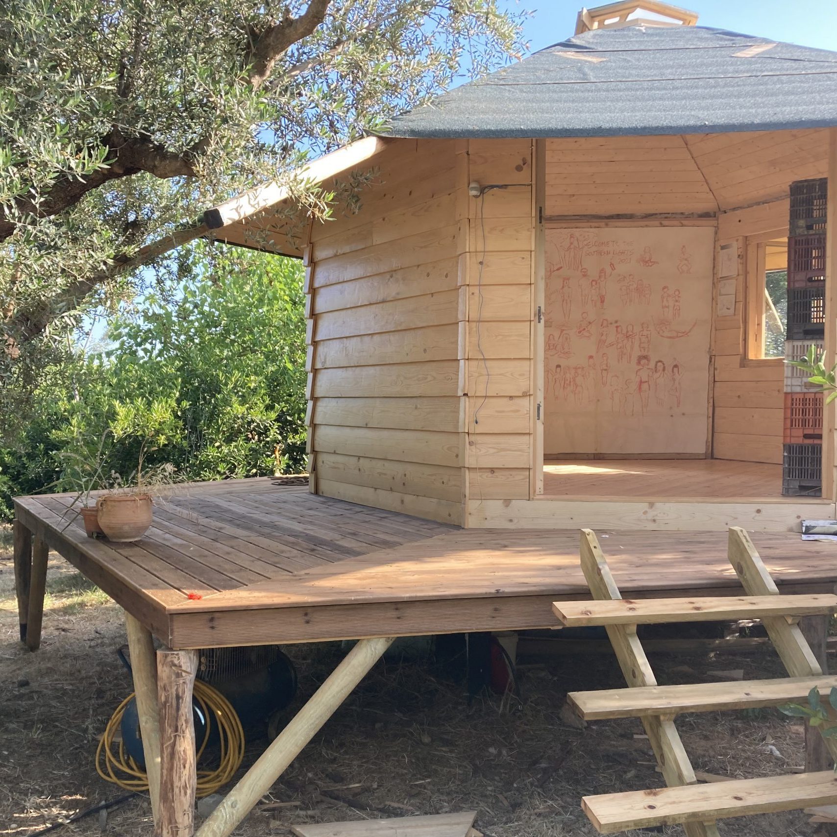 Le mini habitat sur pilotis avec sa terrasse en bois, entre les arbres