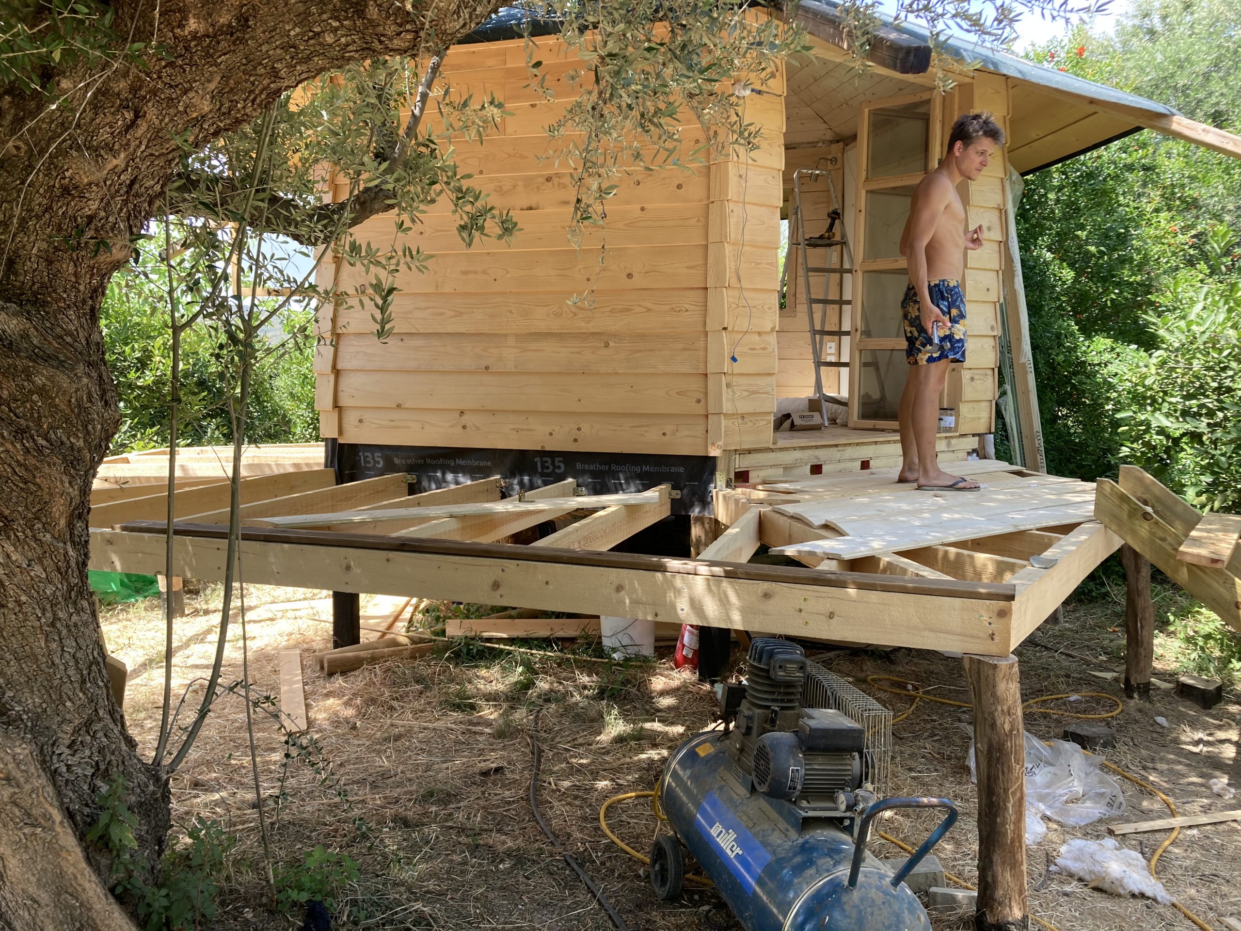 Le mini habitat en construction sur sa plateforme surélevée, une personne debout