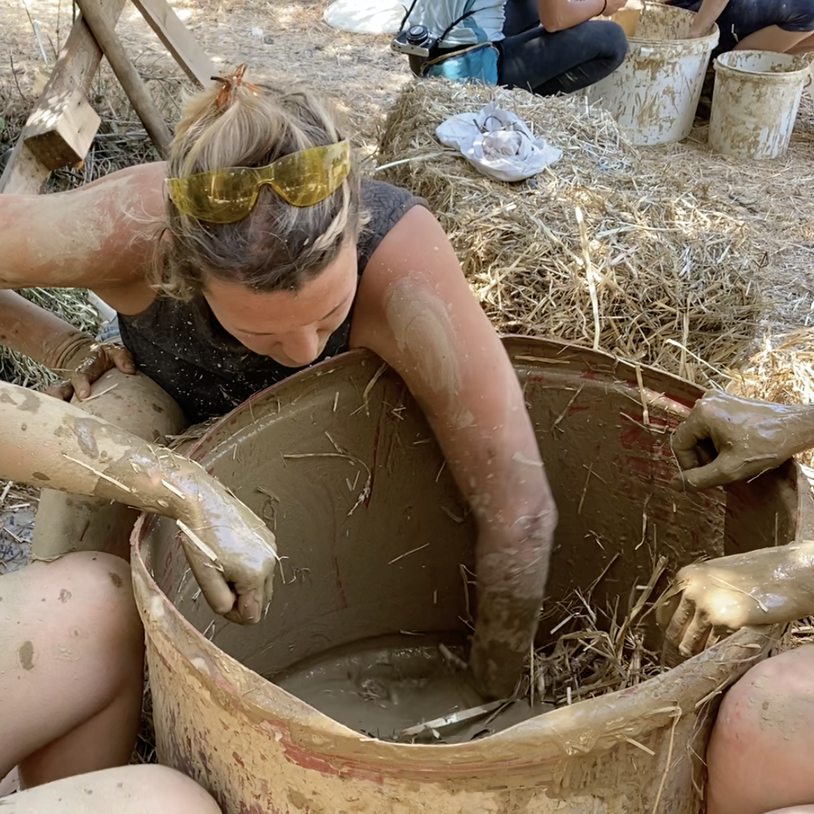 Une participante mélange la terre-paille à la main dans une bassine