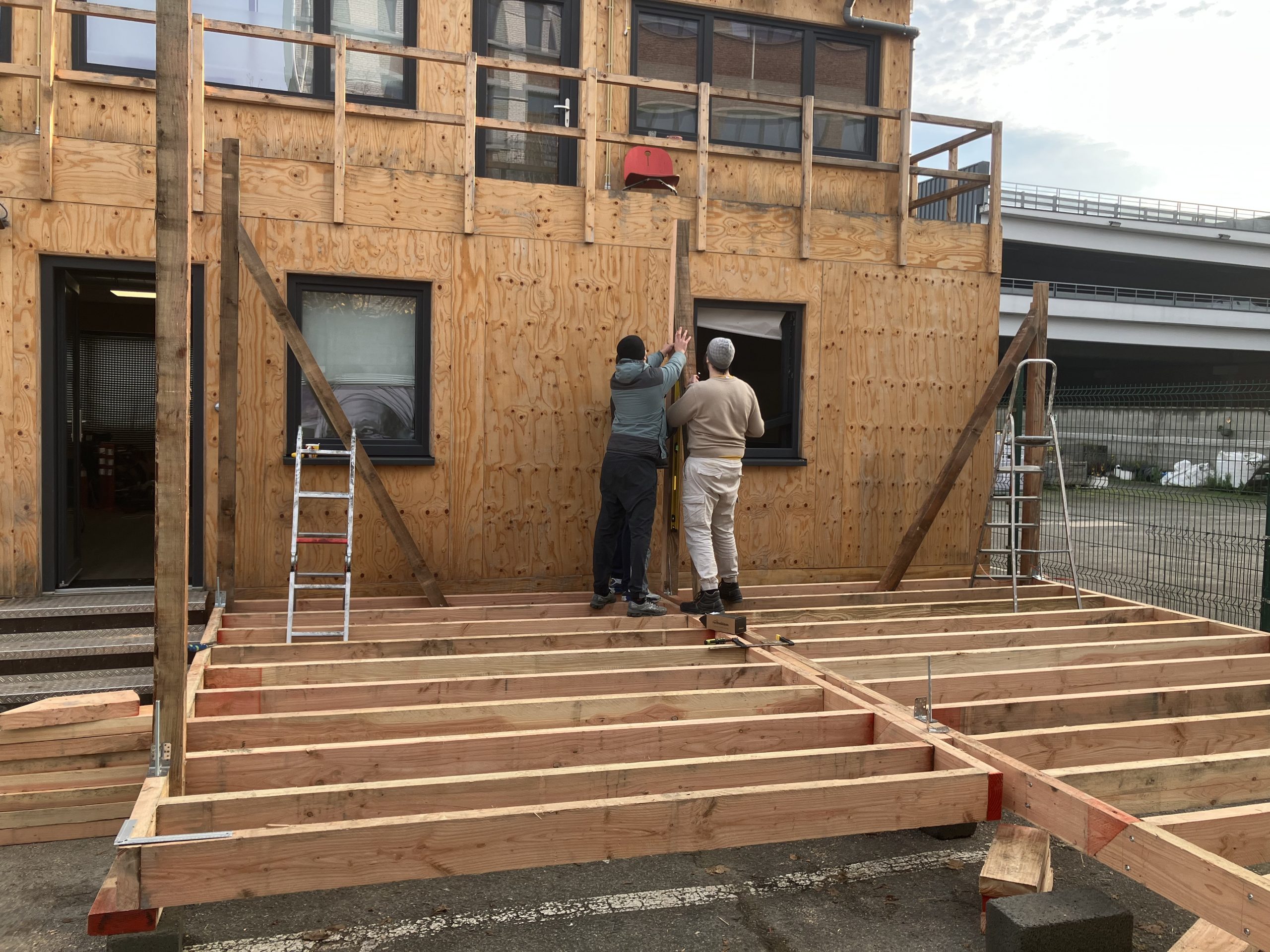 Participants montant l'ossature du plancher contre la façade
