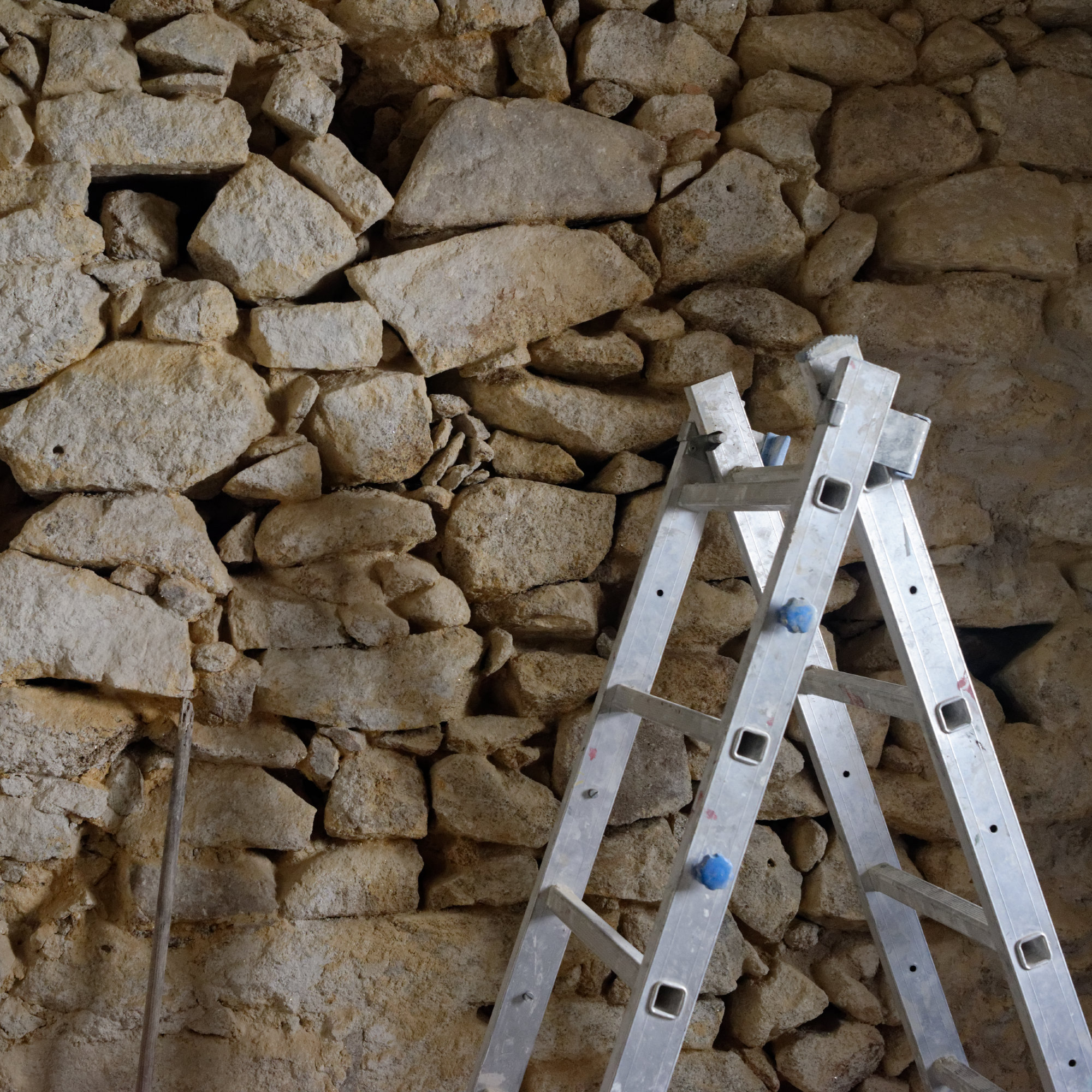 Mur en pierres en cours de rejointoiement, escabeau appuyé