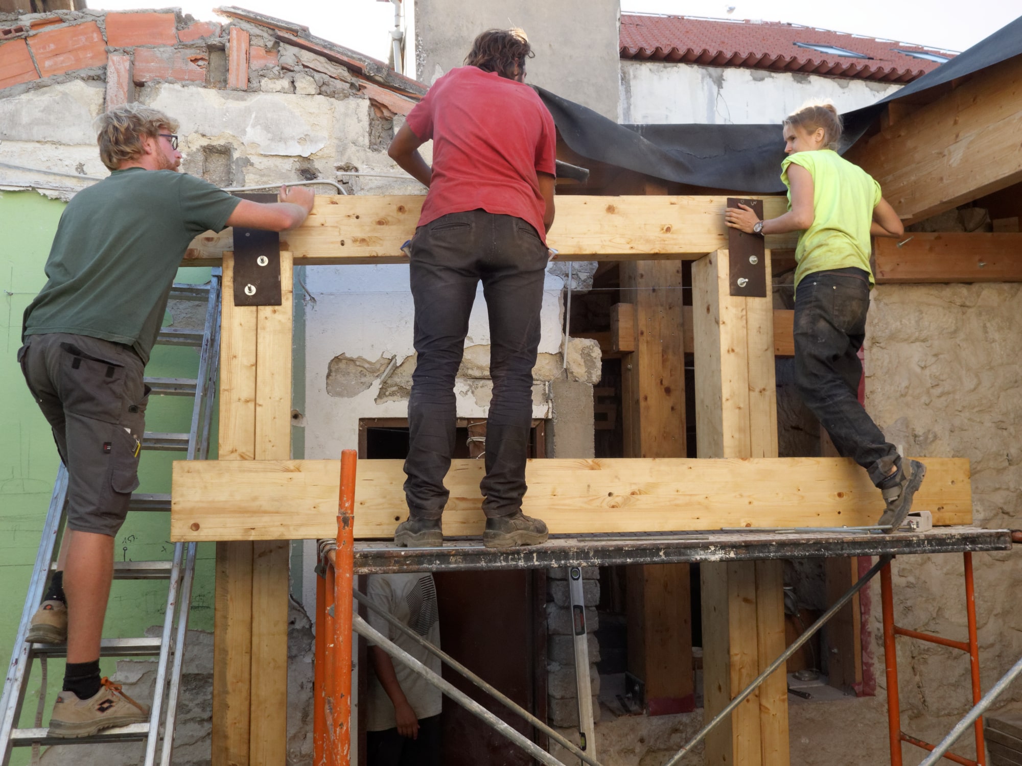 Participants montant une structure bois sur un échafaudage en extérieur