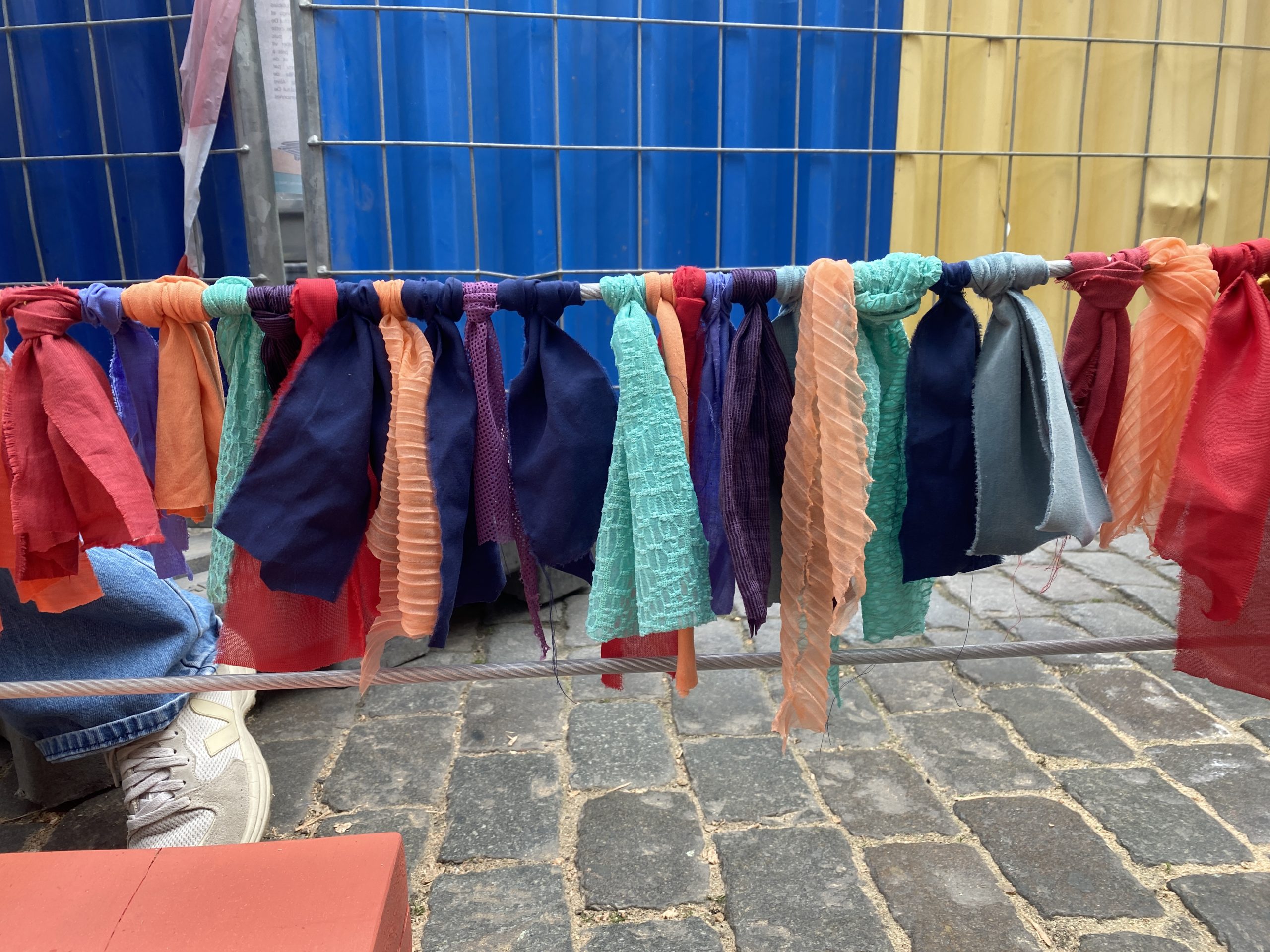 Tissus colorés suspendus à une corde au-dessus des pavés