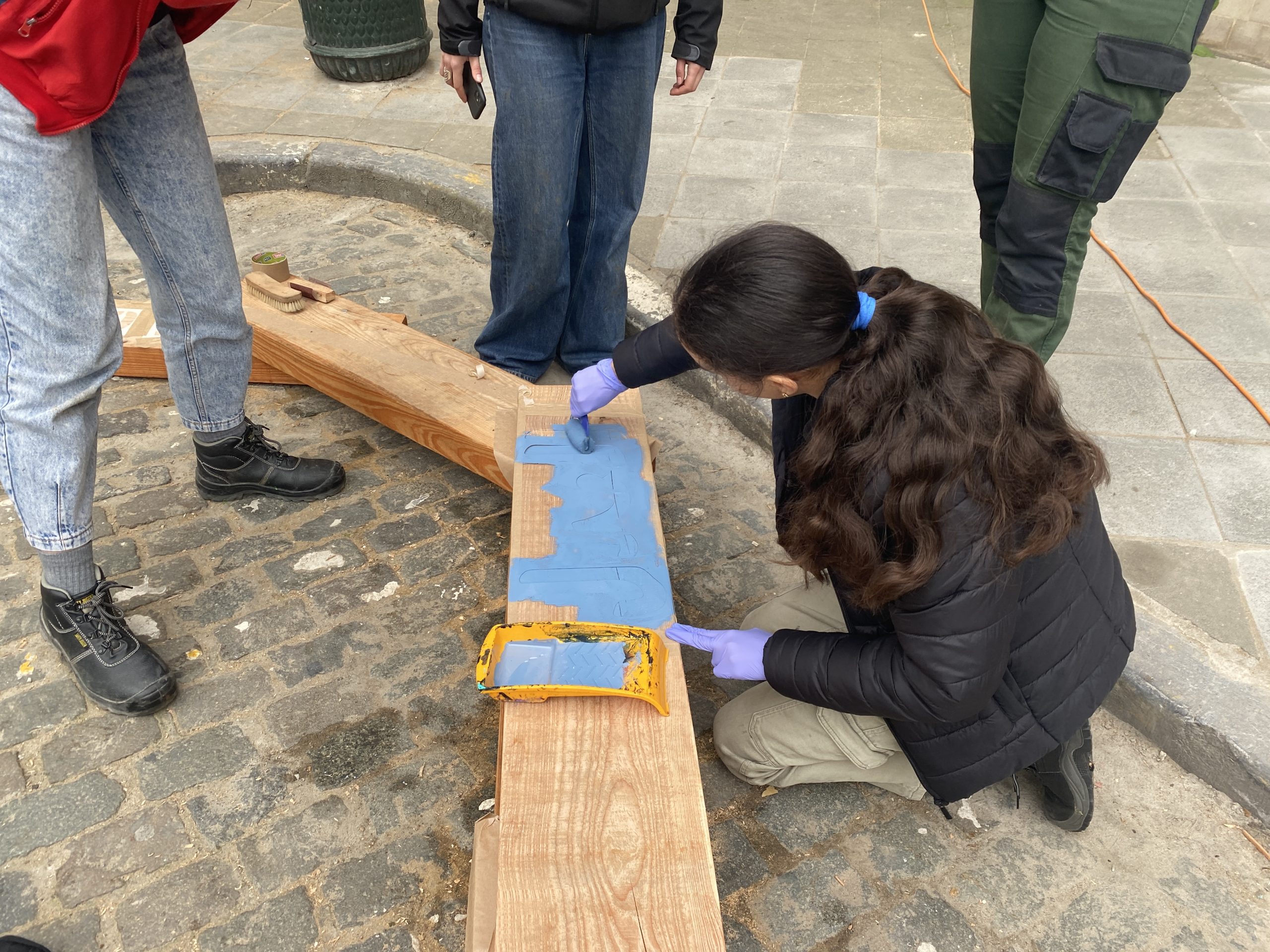 Une participante peint une planche bleue à même le sol