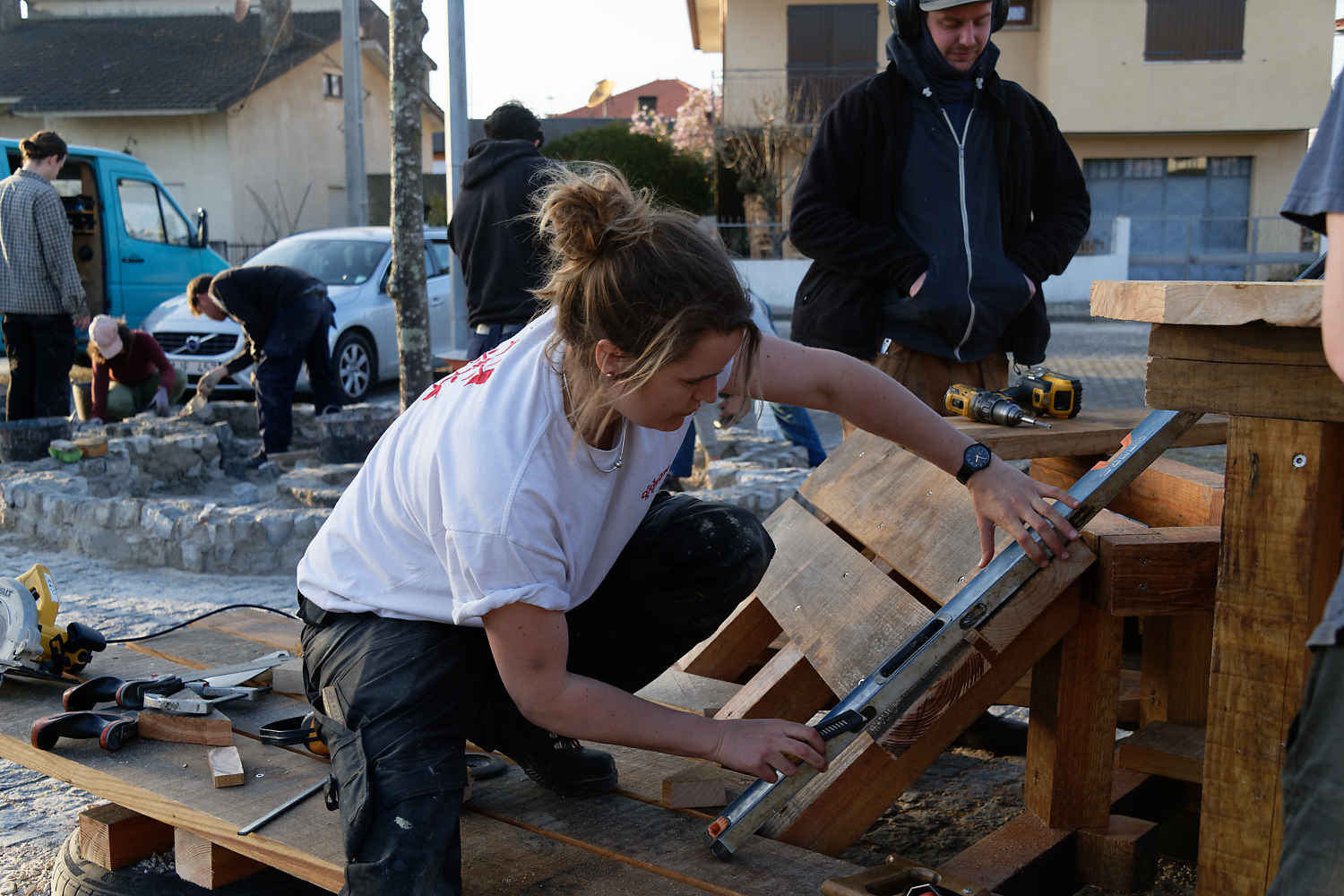 Une participante découpe une planche sur un tréteau