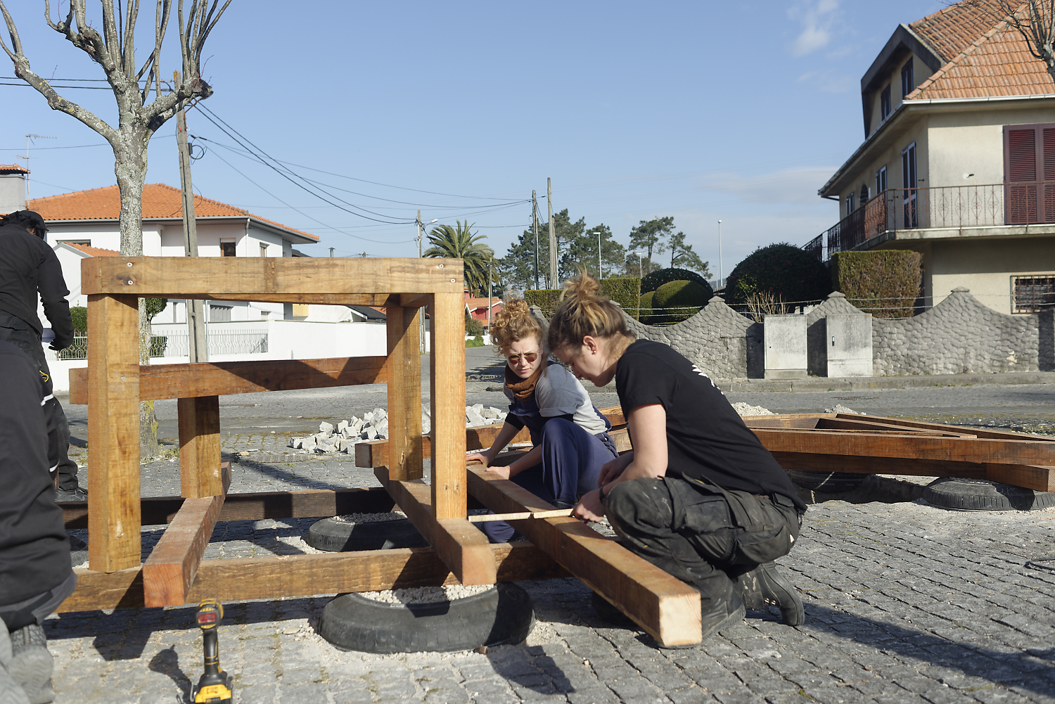 Participants travaillant les tréteaux bois, arbres en fond