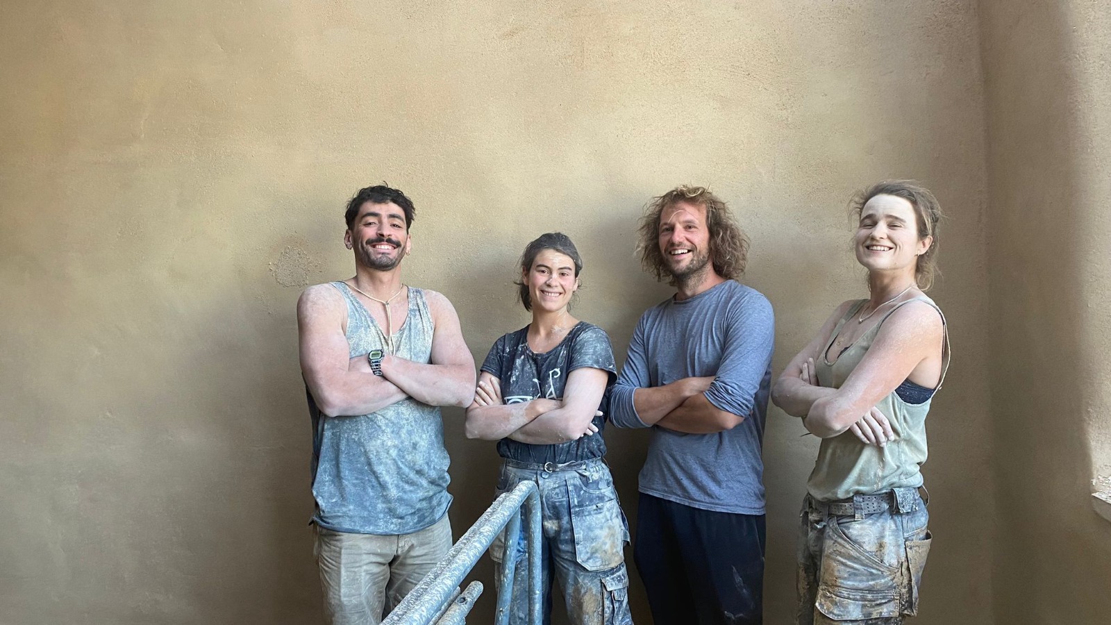 Quatre participants posent devant un mur fraîchement enduit en argile