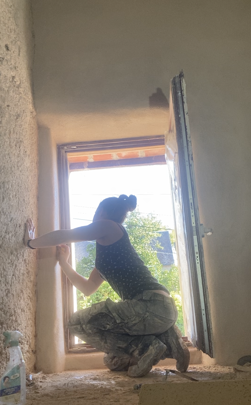 Une participante enduit l'embrasure d'une porte baignée de lumière