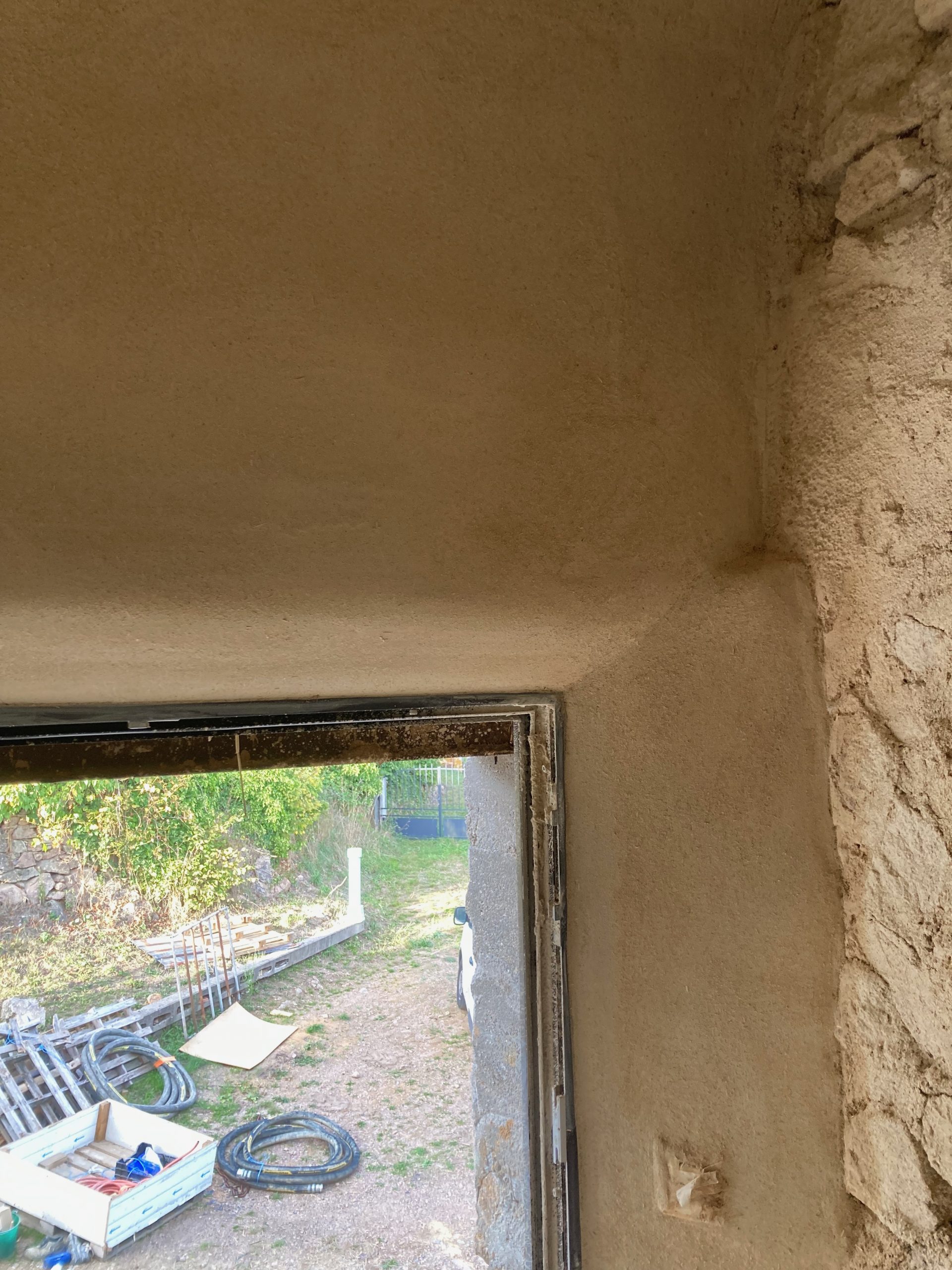 Embrasure de porte enduite en argile ouvrant sur l'extérieur