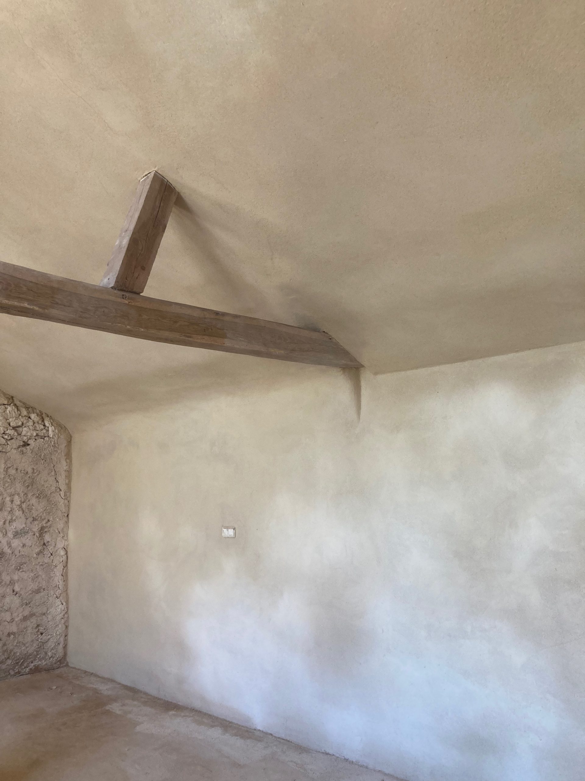 Angle de mur enduit en argile sous la charpente