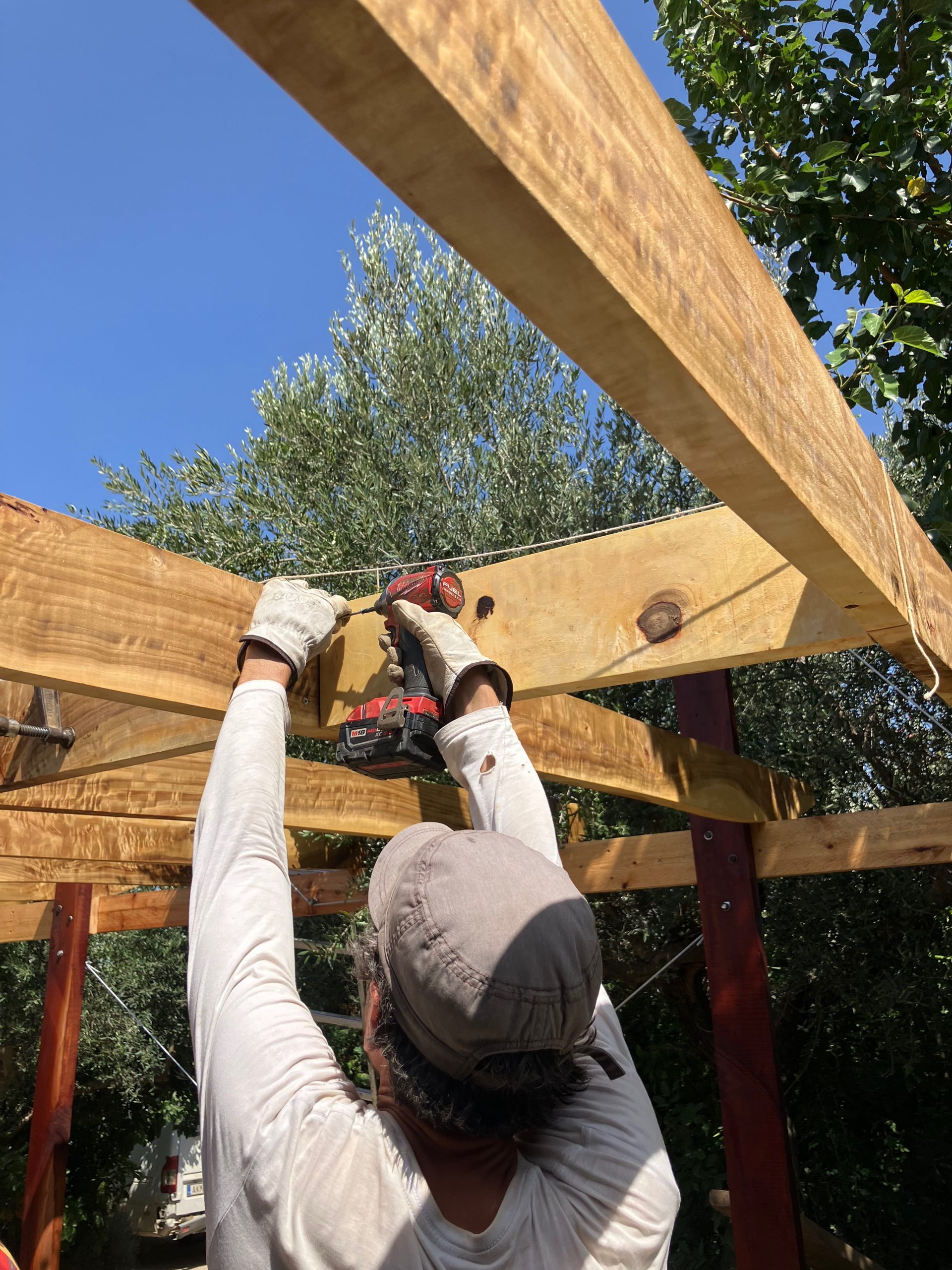 Un participant fixe une traverse en hauteur, bras levés