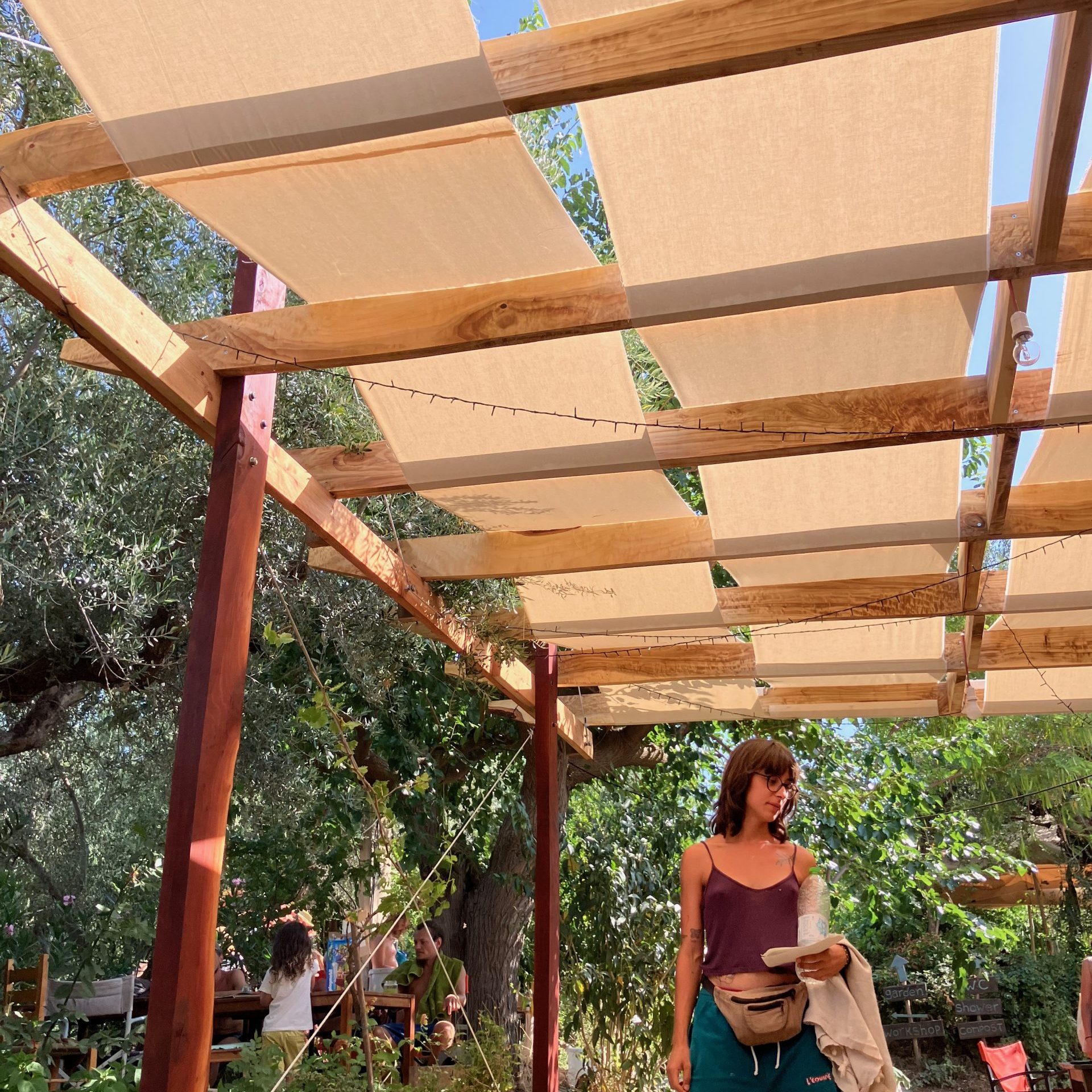 Une personne sous la pergola achevée, jardin en fond